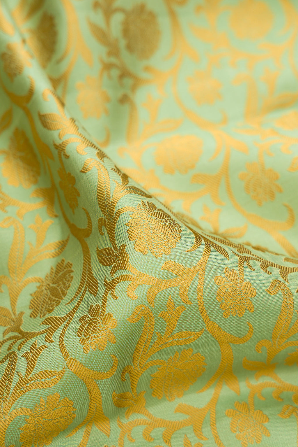 Close up of Pure Silk Pure Zari Pista Green Kanjivaram Saree with Jacquard design on the body and Zari And Thread Border.  displaying folds