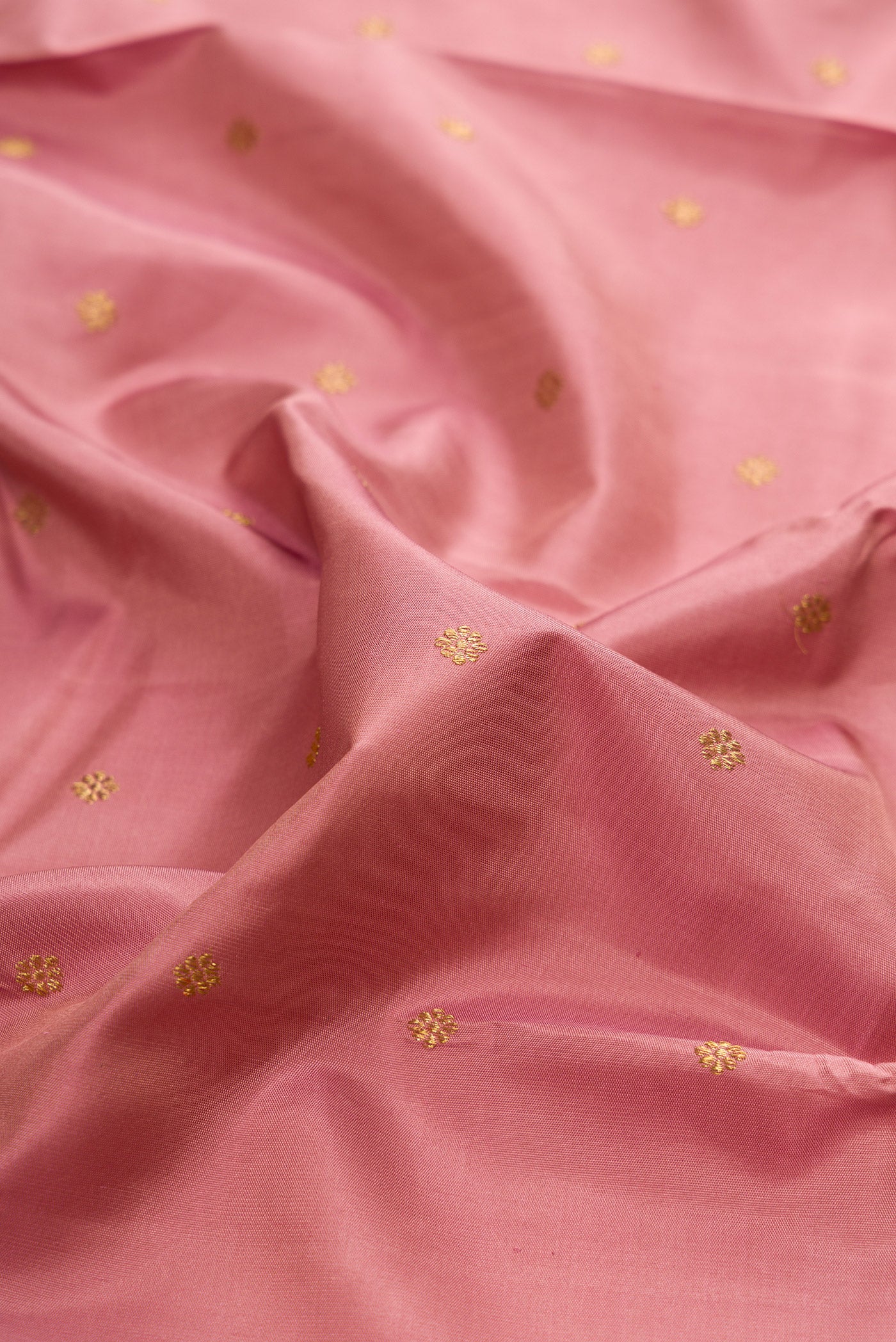 Close up of Pure Silk Pure Zari Rose Gold Kanjivaram Saree with Zari Butta on the body and Zari Border.  displaying folds
