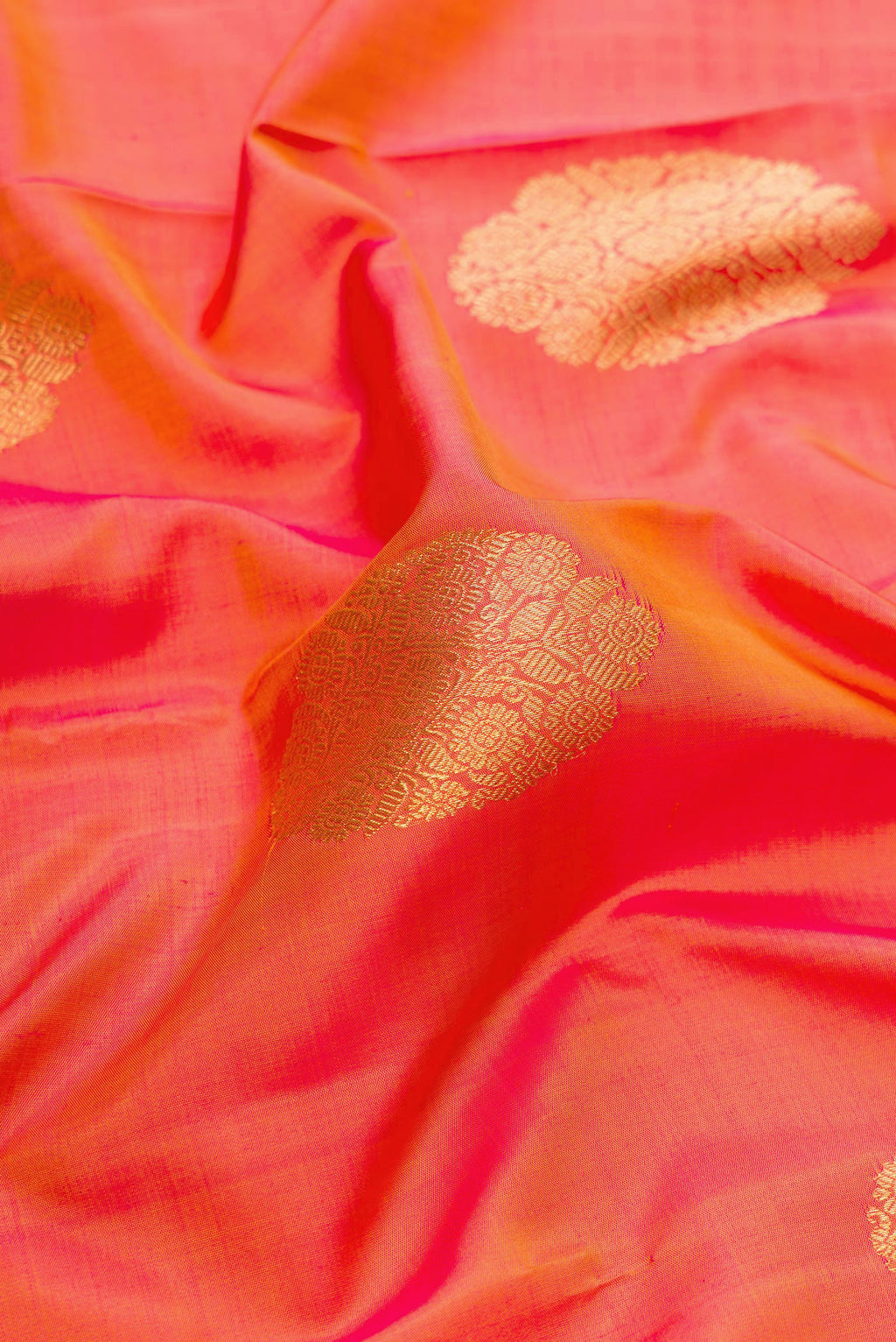 Close up of Pure Silk Pure Zari Brick Orange Dual Tone Kanjivaram Saree with Zari Butta on the body and Zari Border.  displaying folds