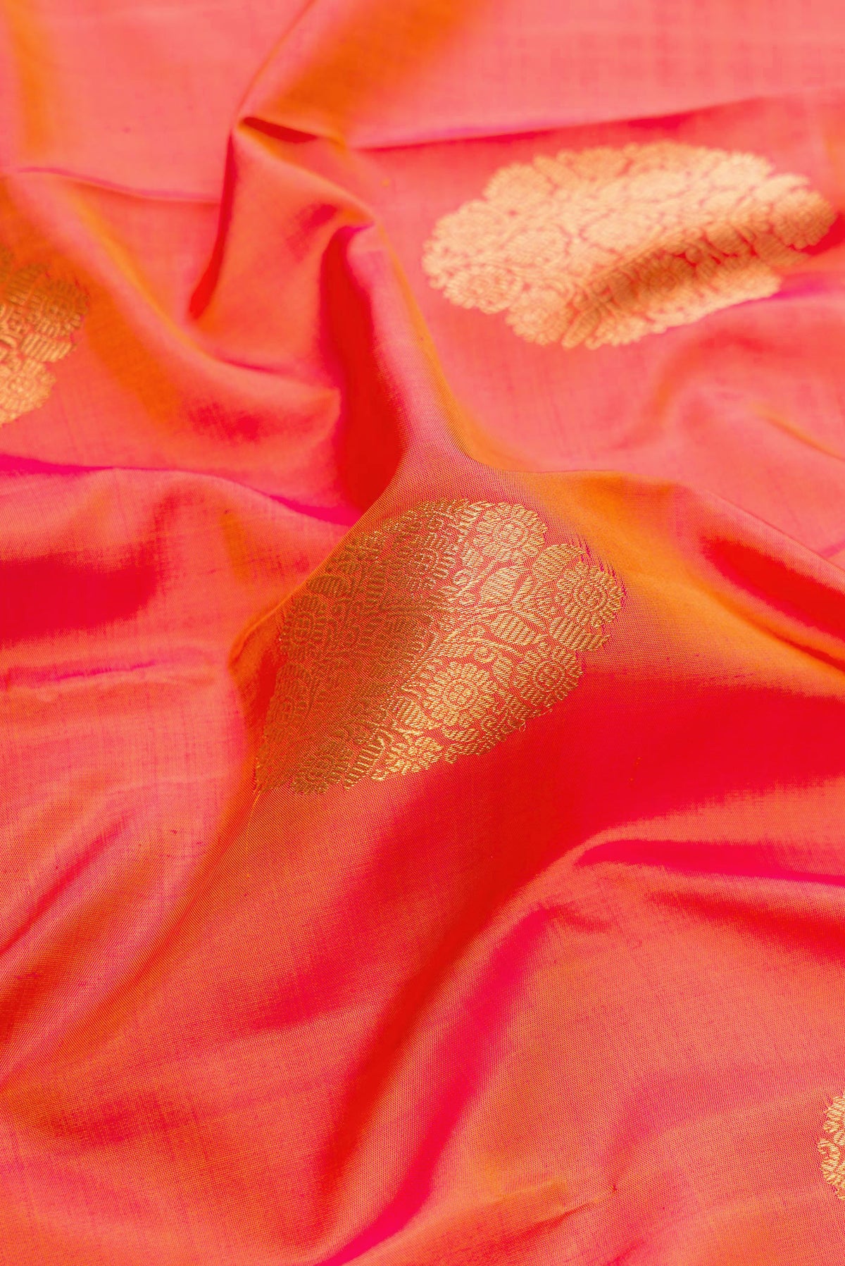 Close up of Pure Silk Pure Zari Brick Orange Dual Tone Kanjivaram Saree with Zari Butta on the body and Zari Border.  displaying folds