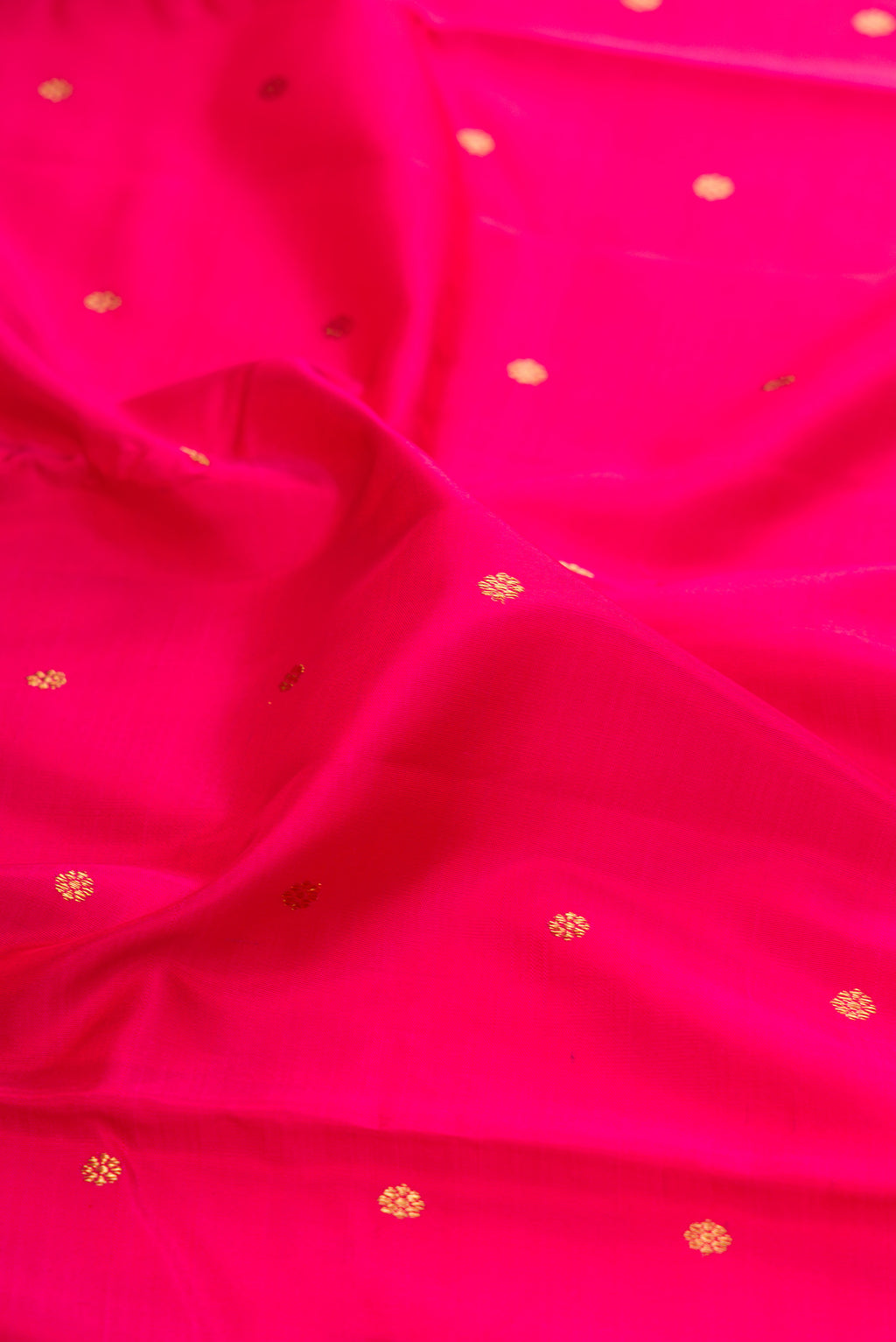 Close up of Pure Silk Pure Zari Dark Pink Kanjivaram Saree with Zari Butta on the body and Zari Border.  displaying folds