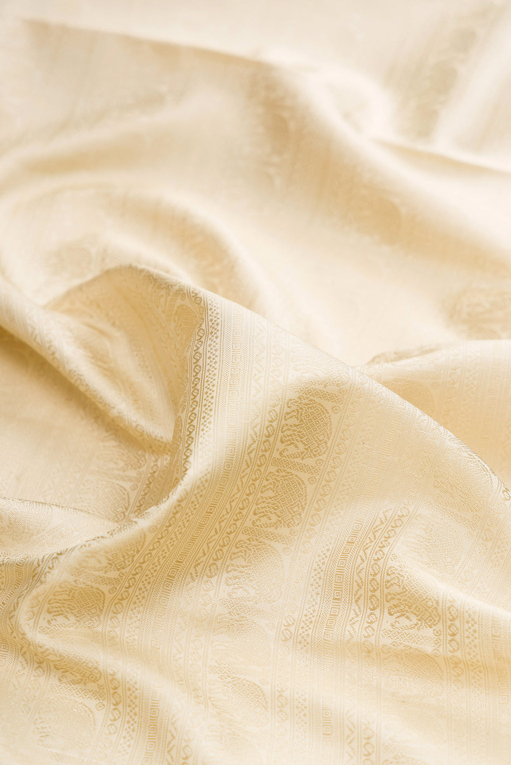 Close up of Pure Silk Pure Zari Cream Kanjivaram Saree with Jacquard design on the body and Fancy Border.  displaying folds