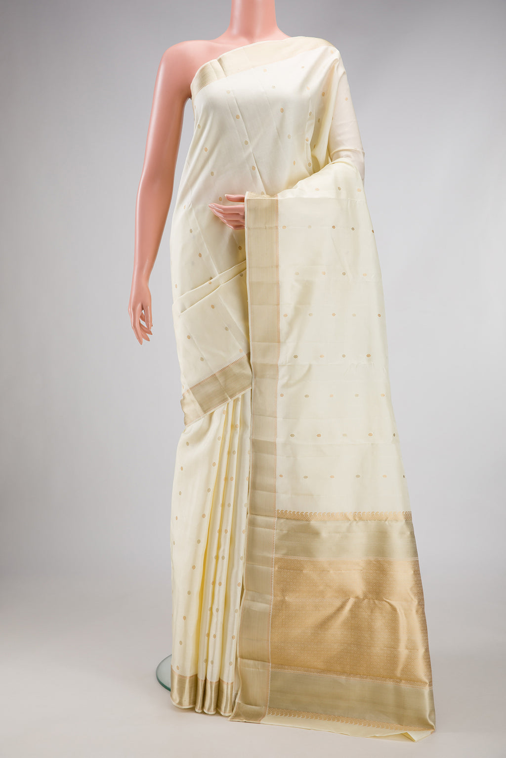 Off White Kanjivaram Silk Saree with Thread Butta on the body and Thread Border.  displayed on a mannequin