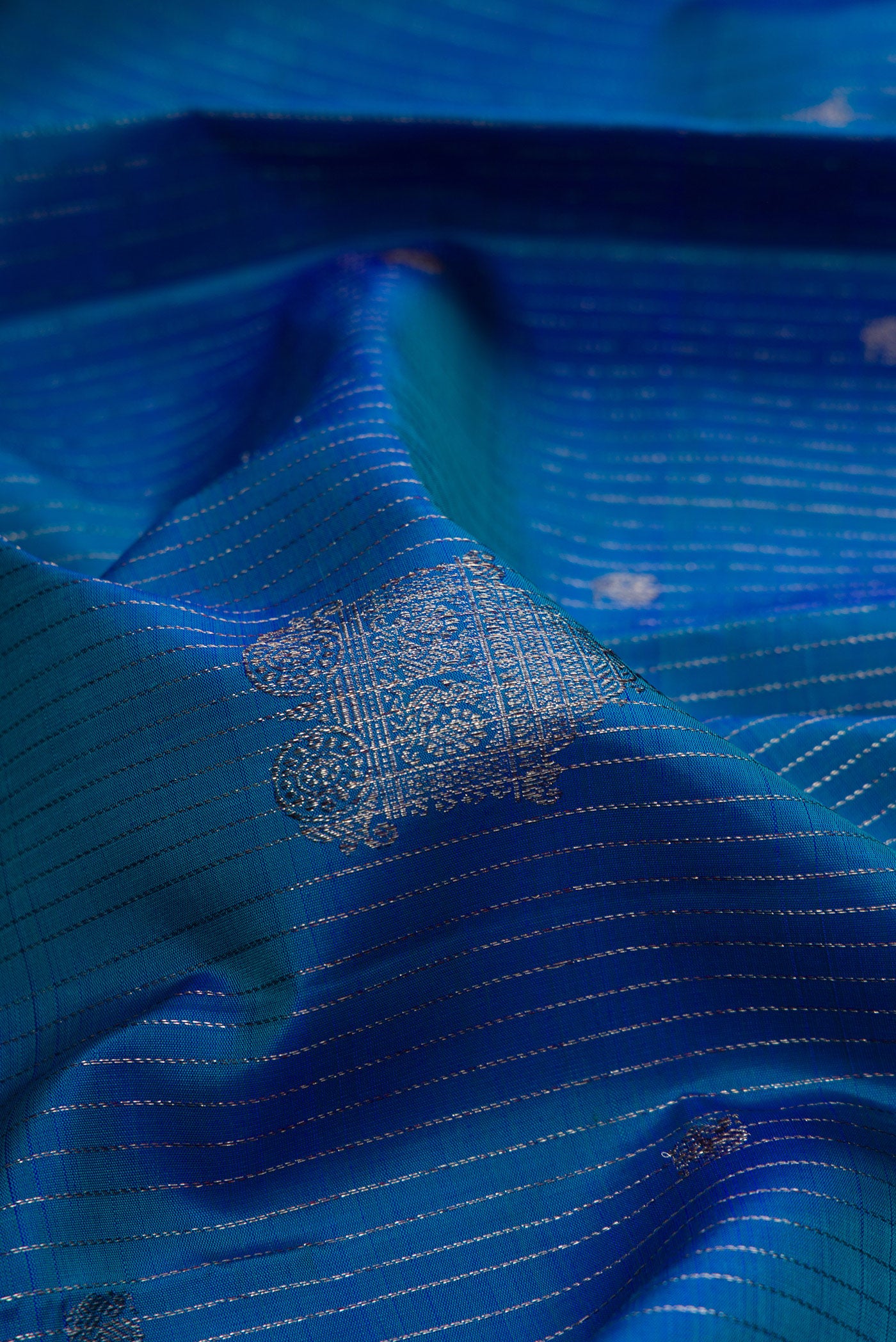 Close up of Peacock Blue Dual Tone Kanjivaram Silk Saree with Stripes on the body and Without Border.  displaying folds