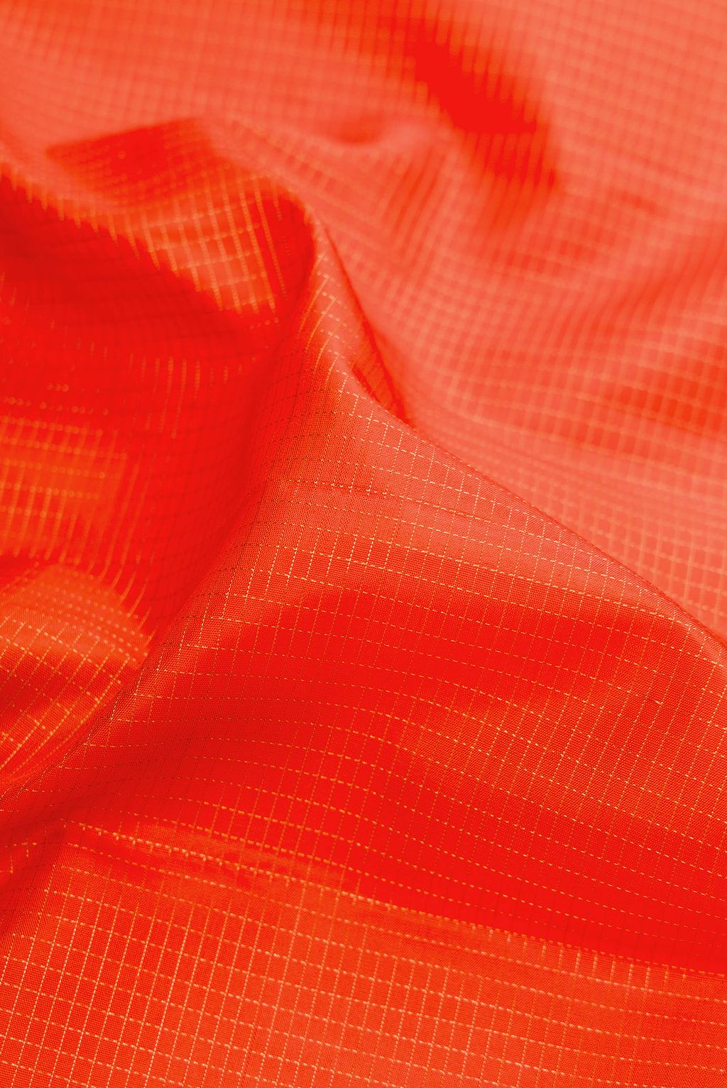 Close up of Orange Kanjivaram Silk Saree with Checked design on the body and Fancy Border.  displaying folds