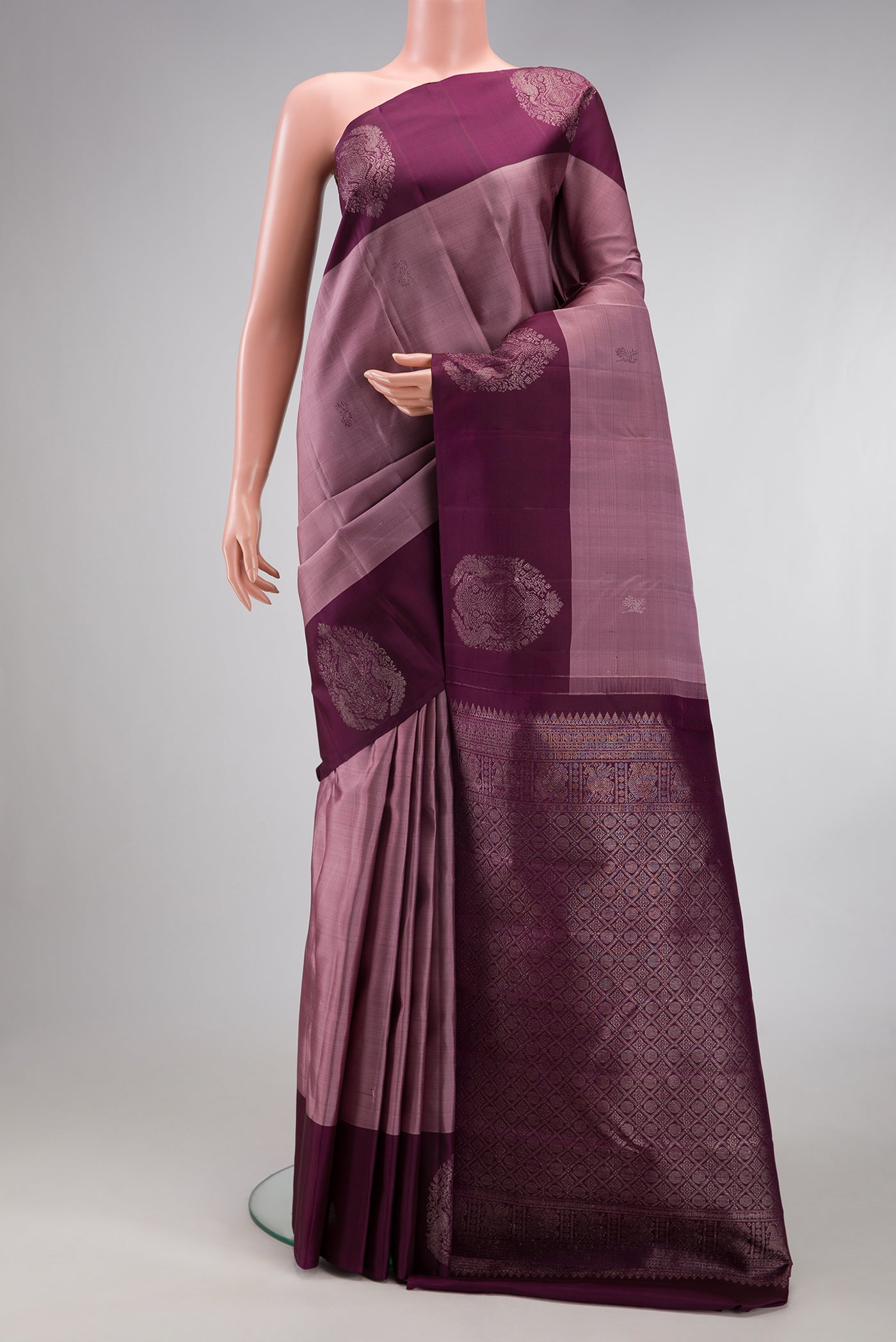 Mauve Kanchipuram Silk Saree with Zari Butta on the body and Fancy Border.  displayed on a mannequin