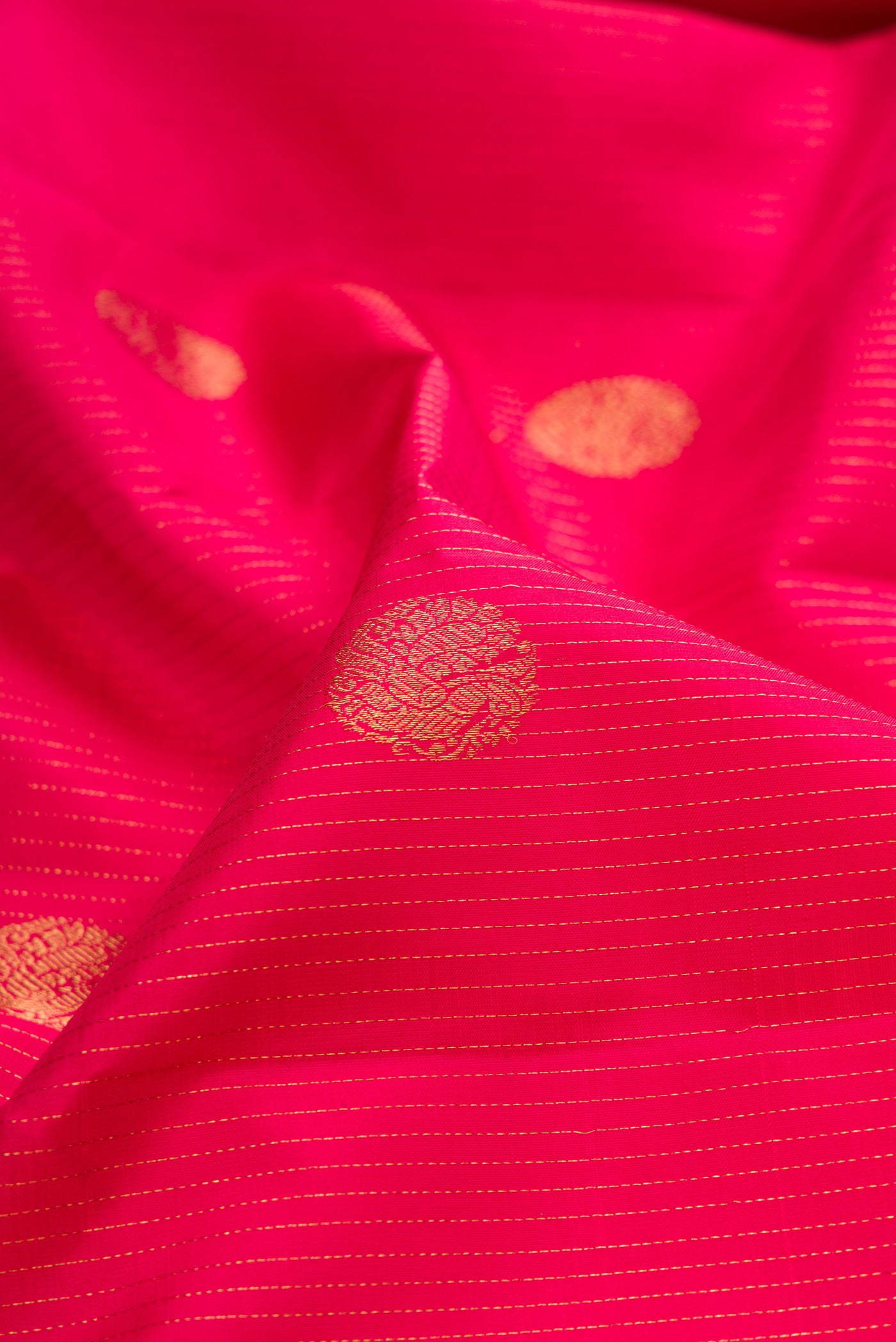 Close up of Dark Pink Kanjivaram Silk Saree with Stripes on the body and Zari Border.  displaying folds