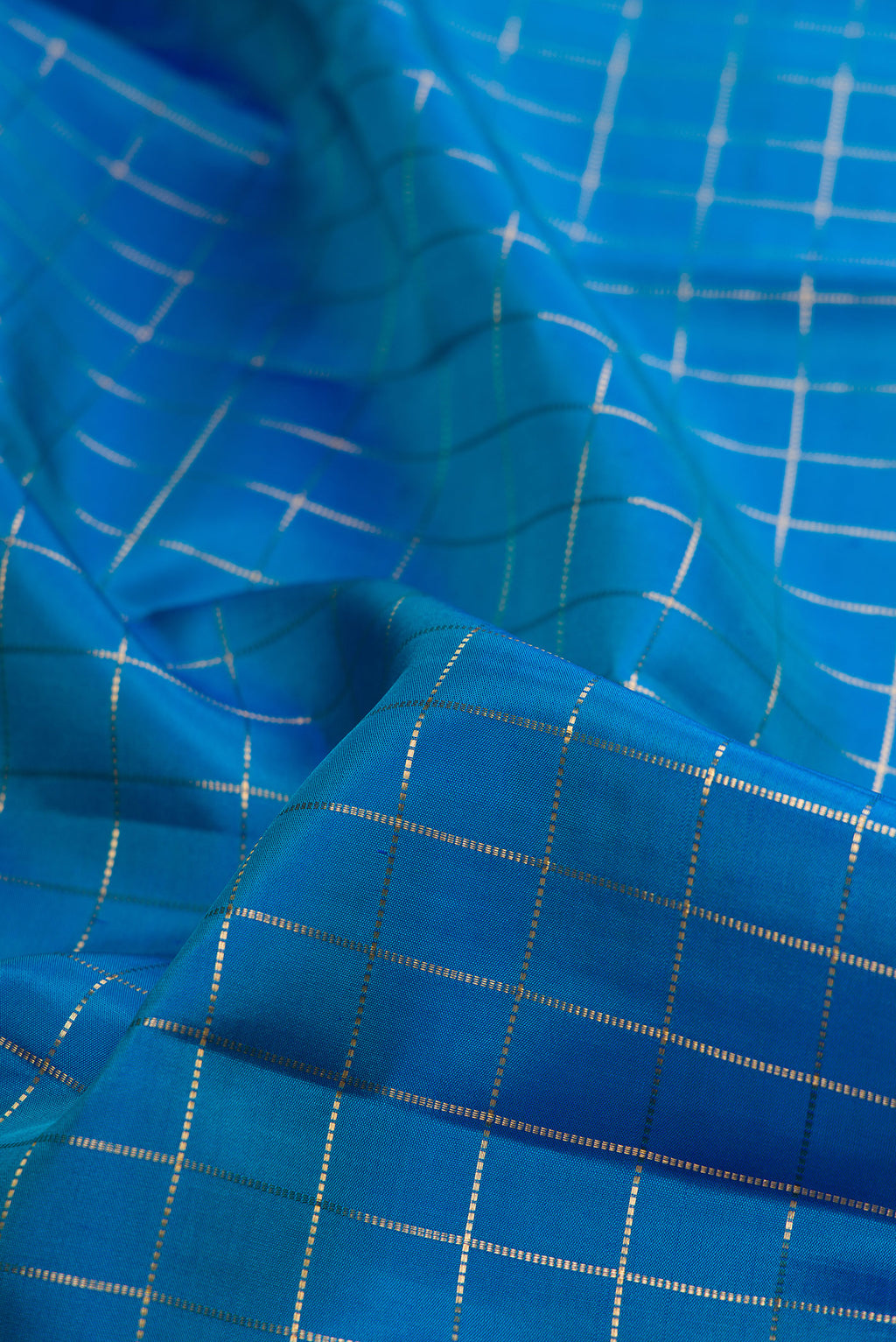Close up of Pure Silk Peacock Blue Kanjivaram Saree with Checked design on the body and Zari Border.  displaying folds