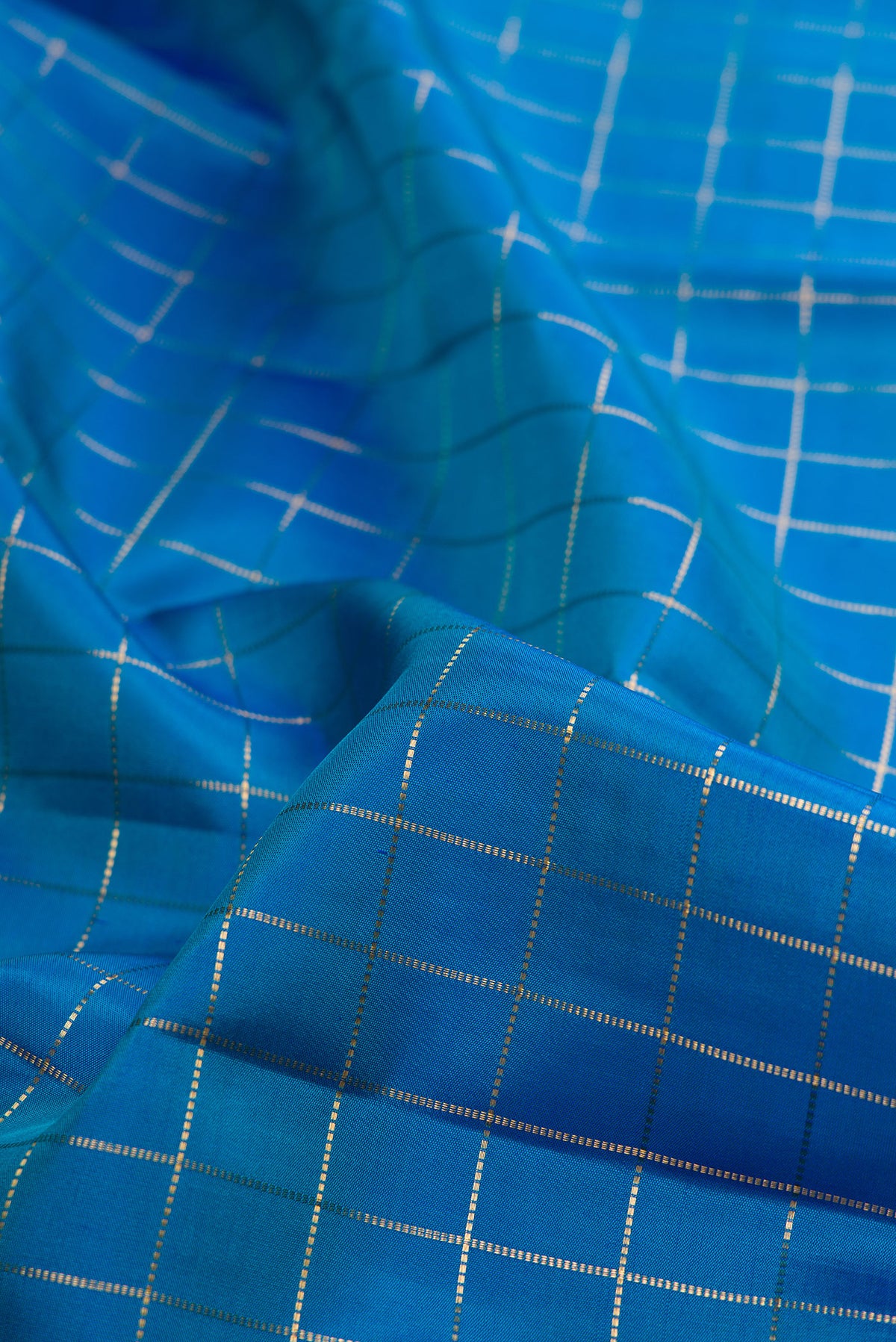Close up of Pure Silk Peacock Blue Kanjivaram Saree with Checked design on the body and Zari Border.  displaying folds