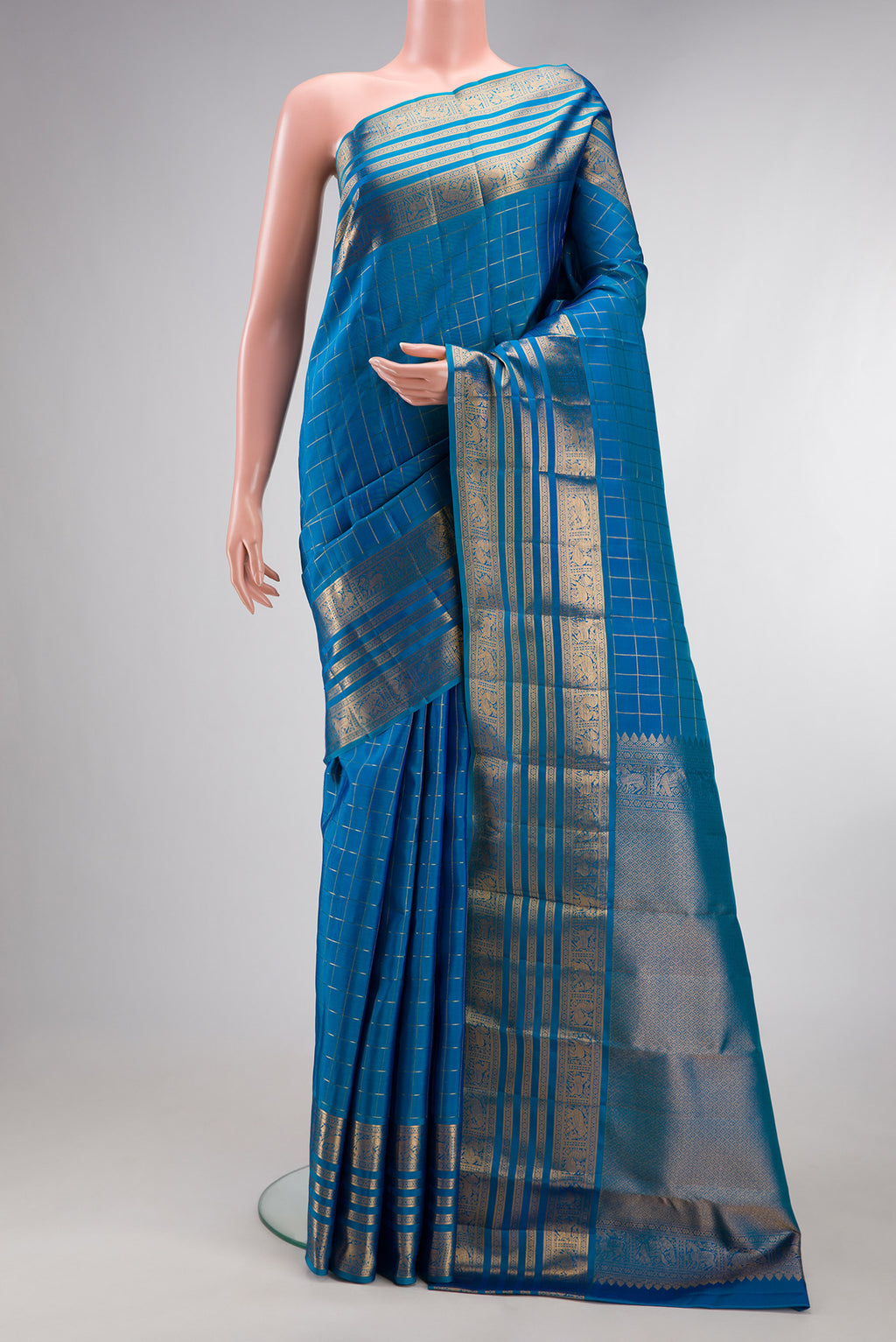 Pure Silk Peacock Blue Kanjivaram Saree with Checked design on the body and Zari Border.  displayed on a mannequin