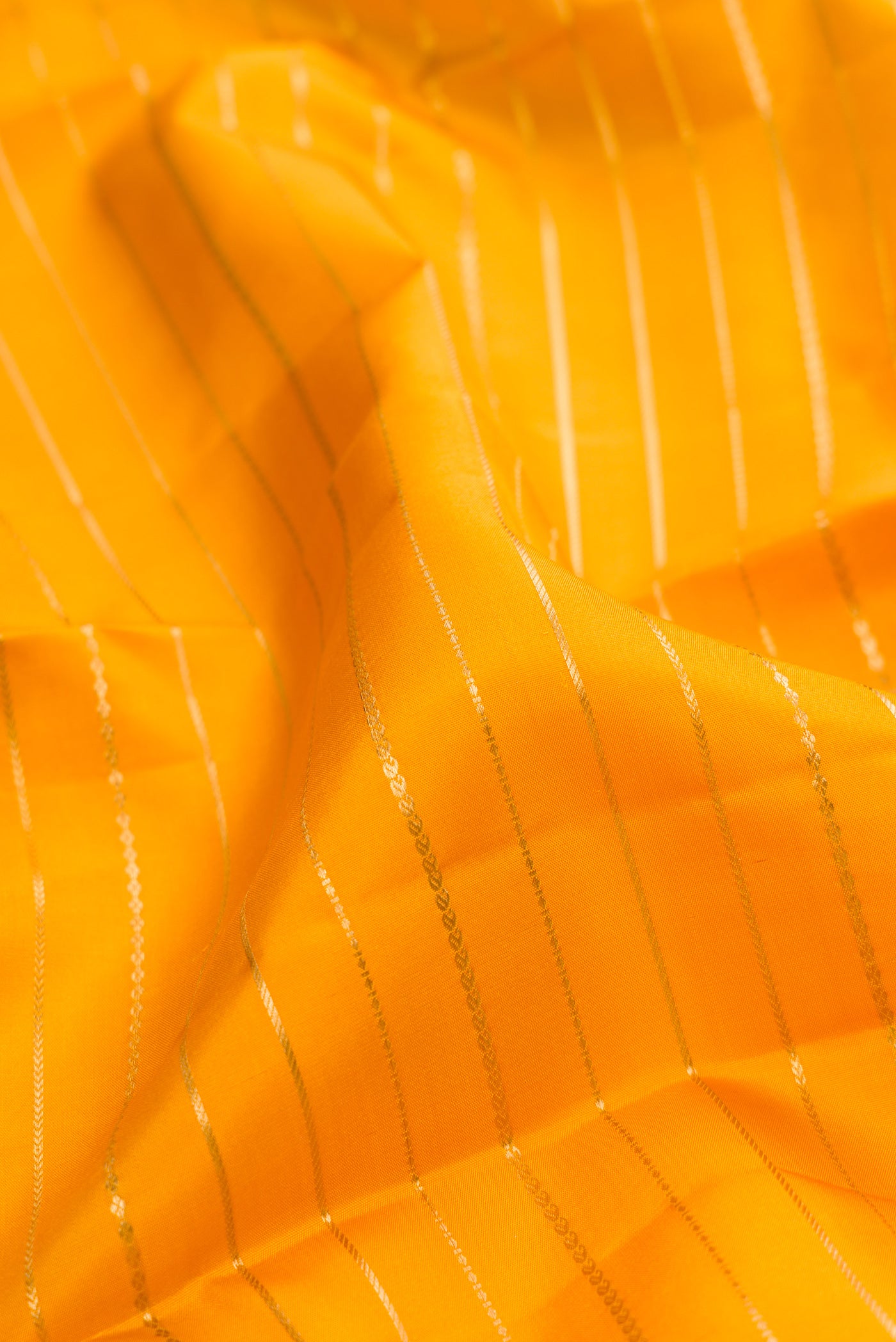 Close up of Mustard Kanjivaram Silk Saree with Veldhari on the body and Fancy Border.  displaying folds