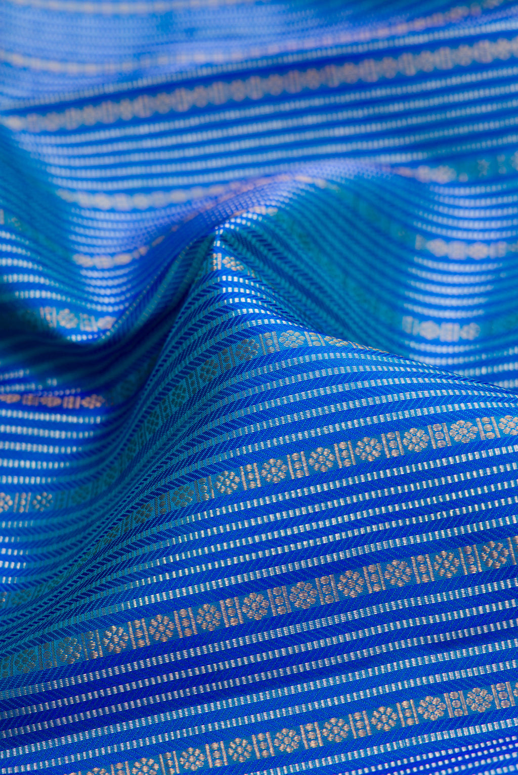 Close up of Peacock Blue Dual Tone Kanjivaram Silk Saree with Stripes on the body and Zari Border.  displaying folds