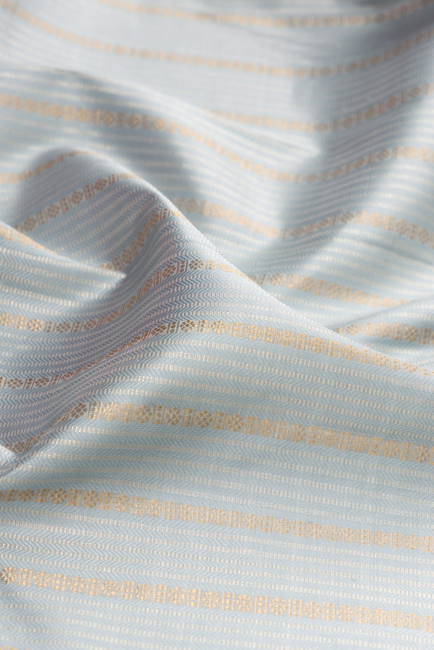Close up of Grey Kanjivaram Silk Saree with Stripes on the body and Zari Border.  displaying folds