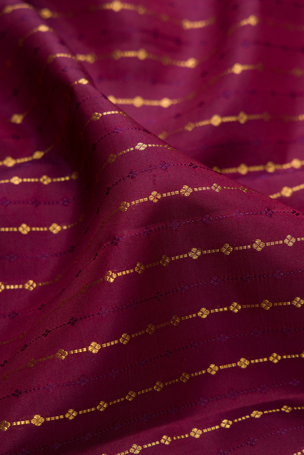 Close up of Burgundy Kanjivaram Silk Saree with Zari Butta on the body and Zari Border.  displaying folds
