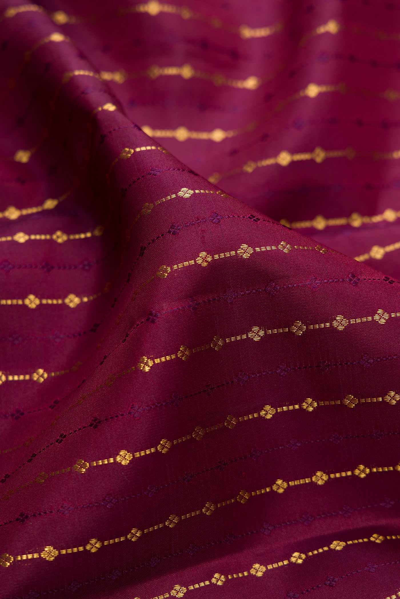 Close up of Burgundy Kanjivaram Silk Saree with Zari Butta on the body and Zari Border.  displaying folds