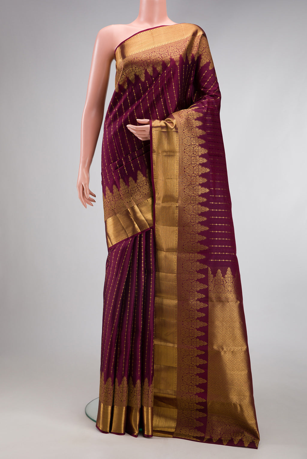Burgundy Kanjivaram Silk Saree with Zari Butta on the body and Zari Border.  displayed on a mannequin
