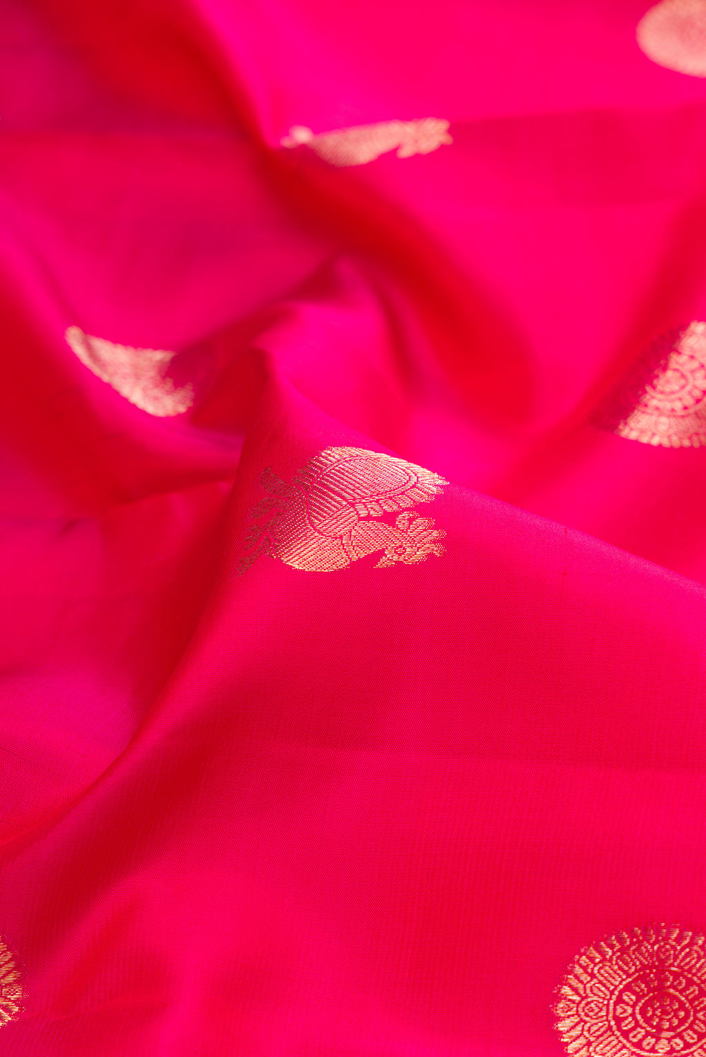 Close up of Dark Pink Kanjivaram Silk Saree with Zari Butta on the body and Zari Border.  displaying folds