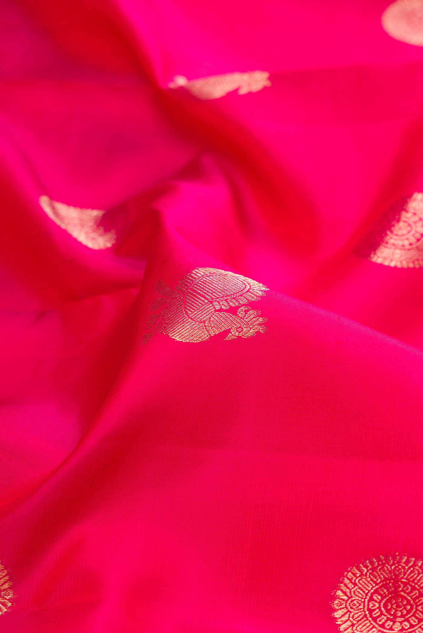 Close up of Dark Pink Kanjivaram Silk Saree with Zari Butta on the body and Zari Border.  displaying folds
