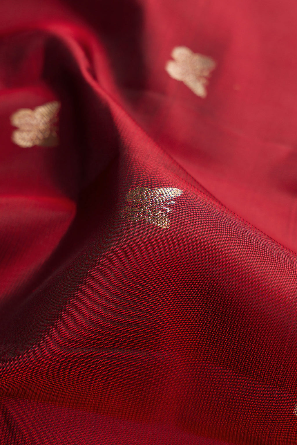 Close up of Maroon Kanjivaram Silk Saree with Zari Butta on the body and Zari Border.  displaying folds