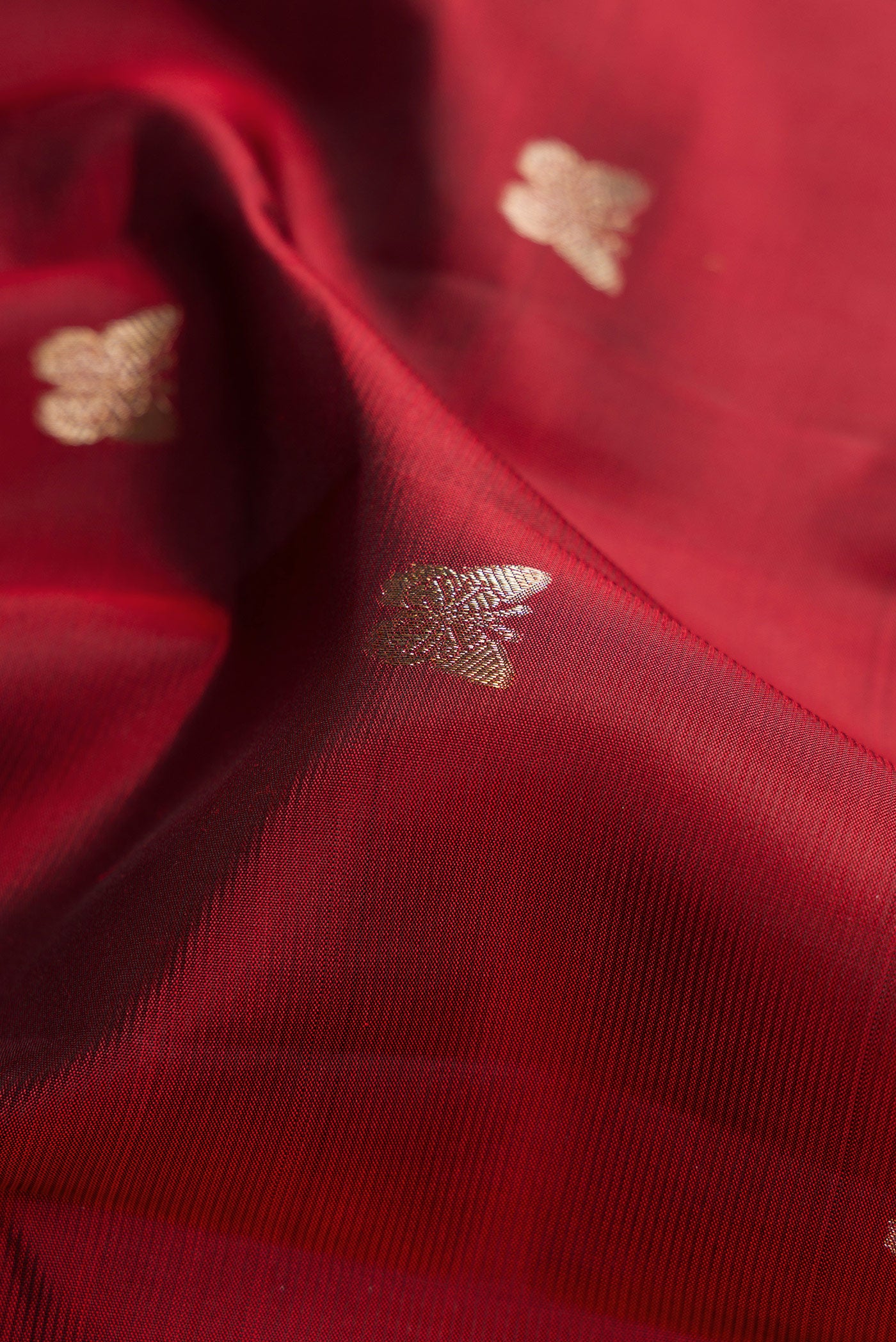 Close up of Maroon Kanjivaram Silk Saree with Zari Butta on the body and Zari Border.  displaying folds