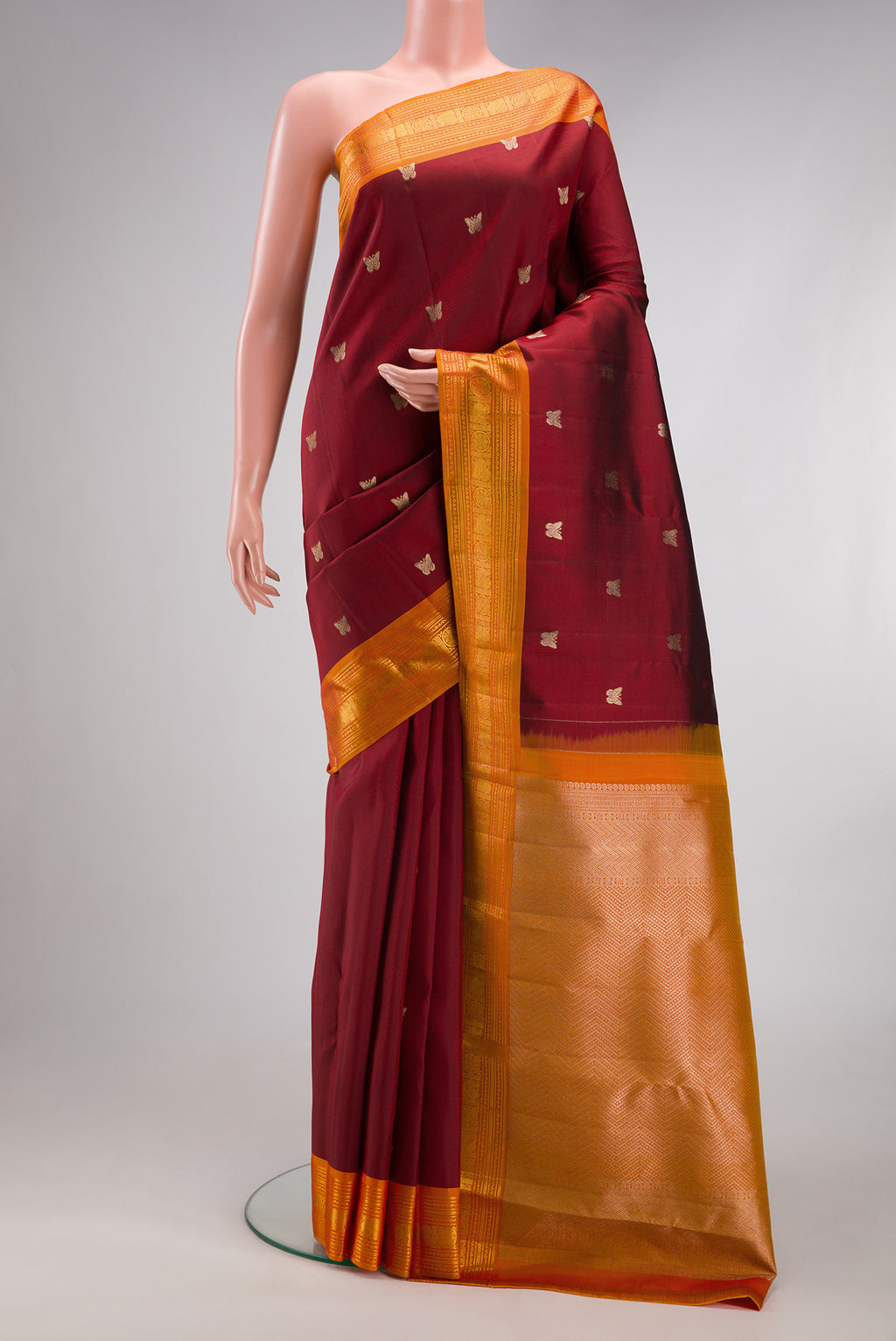 Maroon Kanjivaram Silk Saree with Zari Butta on the body and Zari Border.  displayed on a mannequin