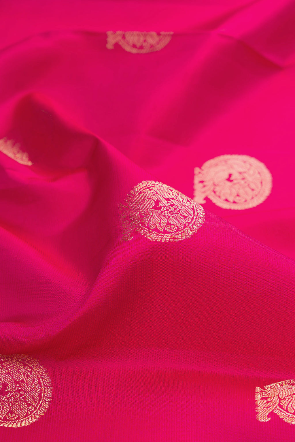 Close up of Dark Pink Kanjivaram Silk Saree with Zari Butta on the body and Zari Border.  displaying folds