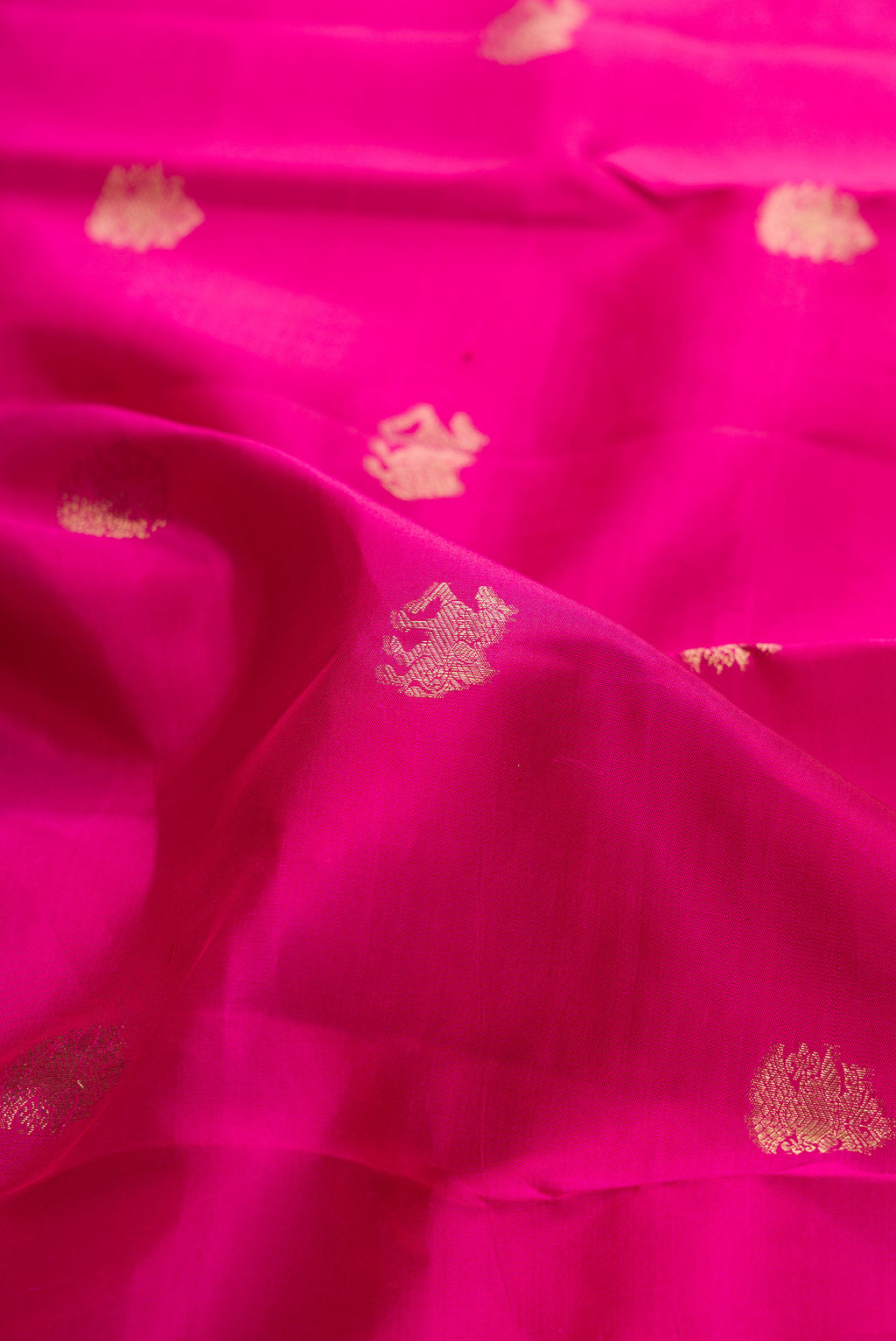 Close up of Dark Pink Kanchipuram Silk Saree with Zari Butta on the body and Zari Border.  displaying folds