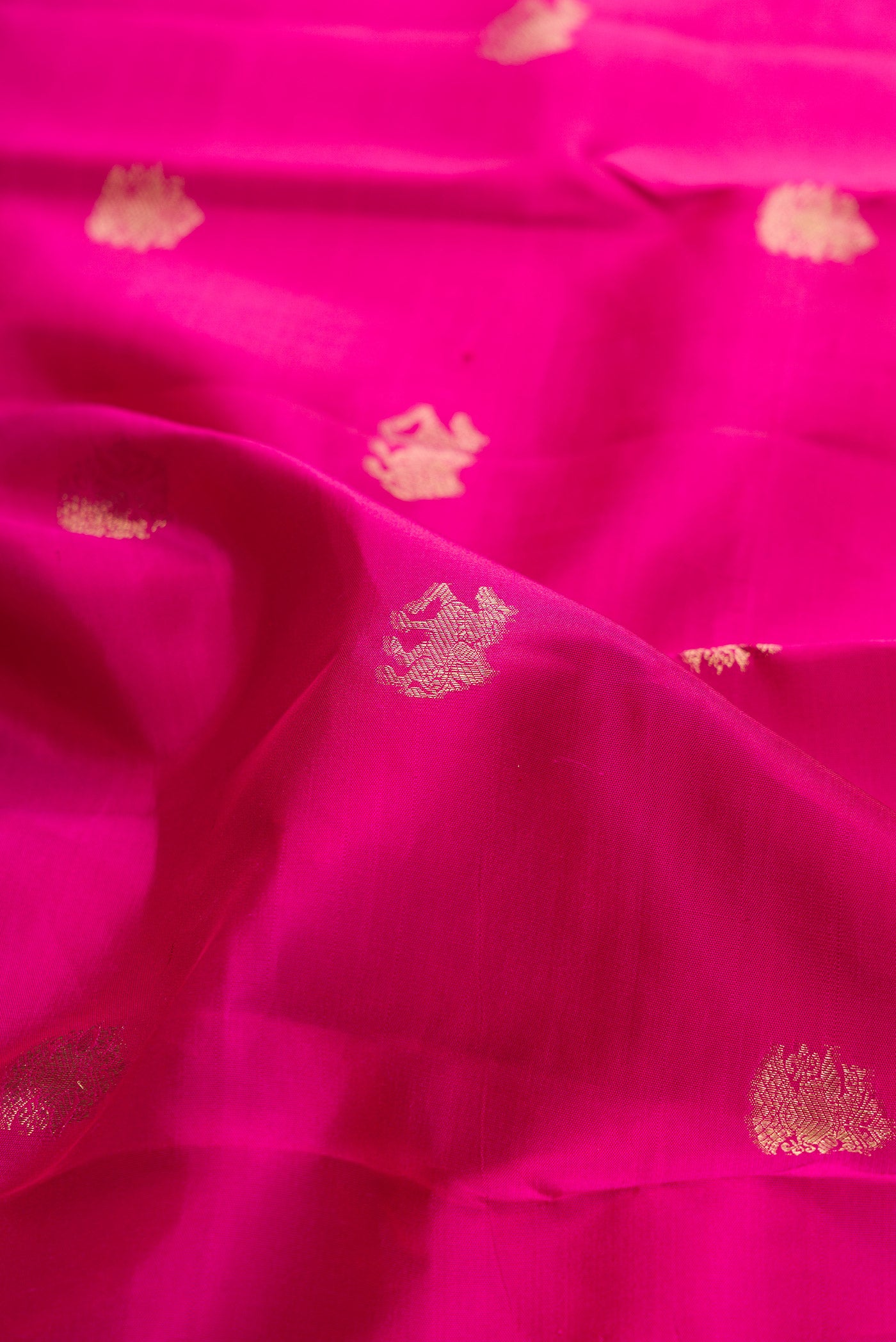 Close up of Dark Pink Kanchipuram Silk Saree with Zari Butta on the body and Zari Border.  displaying folds