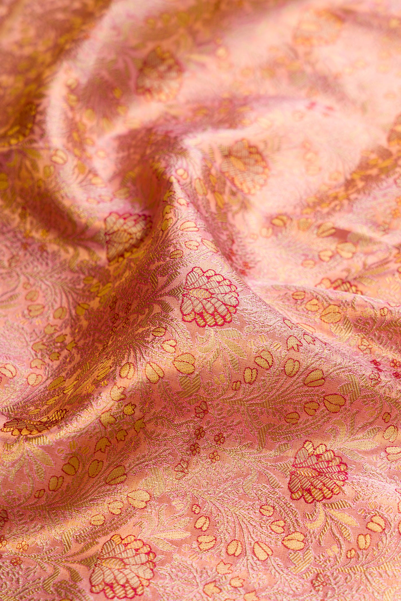 Close up of Rose Gold Dual Tone Kanjivaram Tissue Silk Saree with Zari Brocade on the body and Fancy Border.  displaying folds