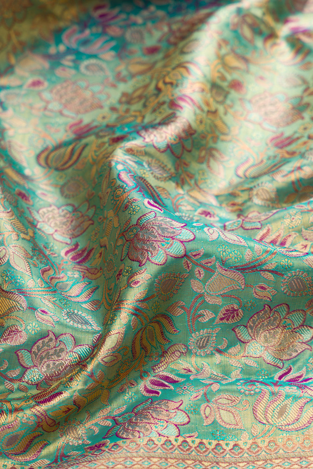 Close up of Turquoise Dual Tone Kanjivaram Tissue Silk Saree with Zari Brocade on the body and Fancy Border.  displaying folds