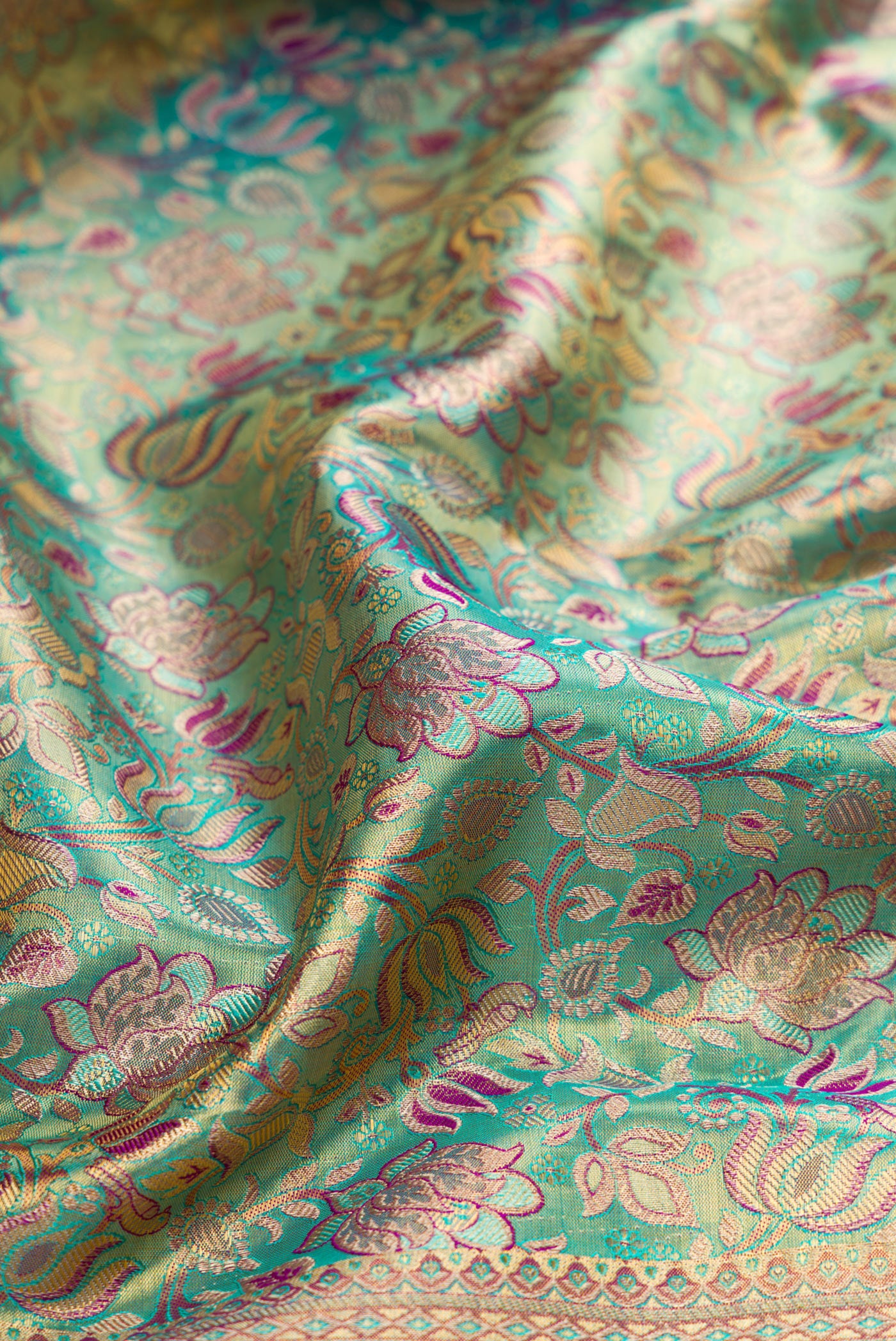 Close up of Turquoise Dual Tone Kanjivaram Tissue Silk Saree with Zari Brocade on the body and Fancy Border.  displaying folds