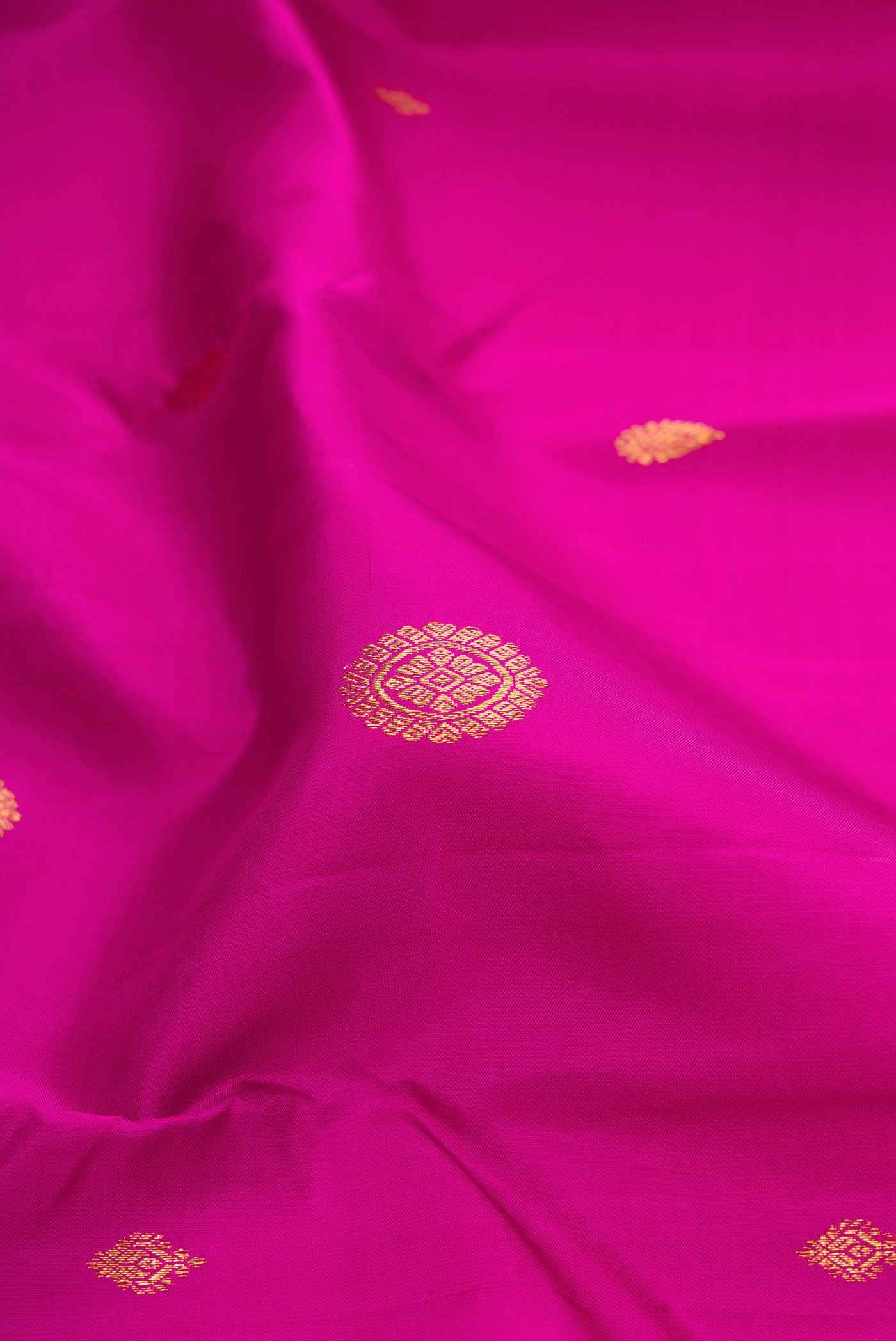 Close up of Magenta Kanchipuram Silk Saree with Zari Butta on the body and Thin Zari Line.  displaying folds