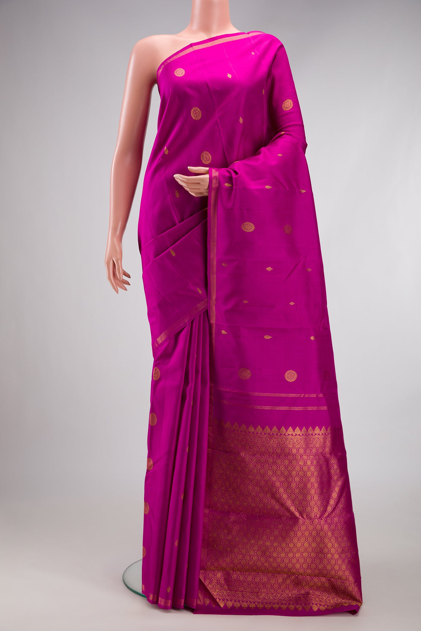 Magenta Kanchipuram Silk Saree with Zari Butta on the body and Thin Zari Line.  displayed on a mannequin