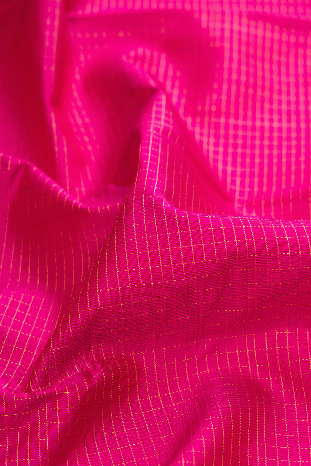 Close up of Pure Silk Rani Pink Kanchipuram Saree with Checked design on the body and Zari Border.  displaying folds