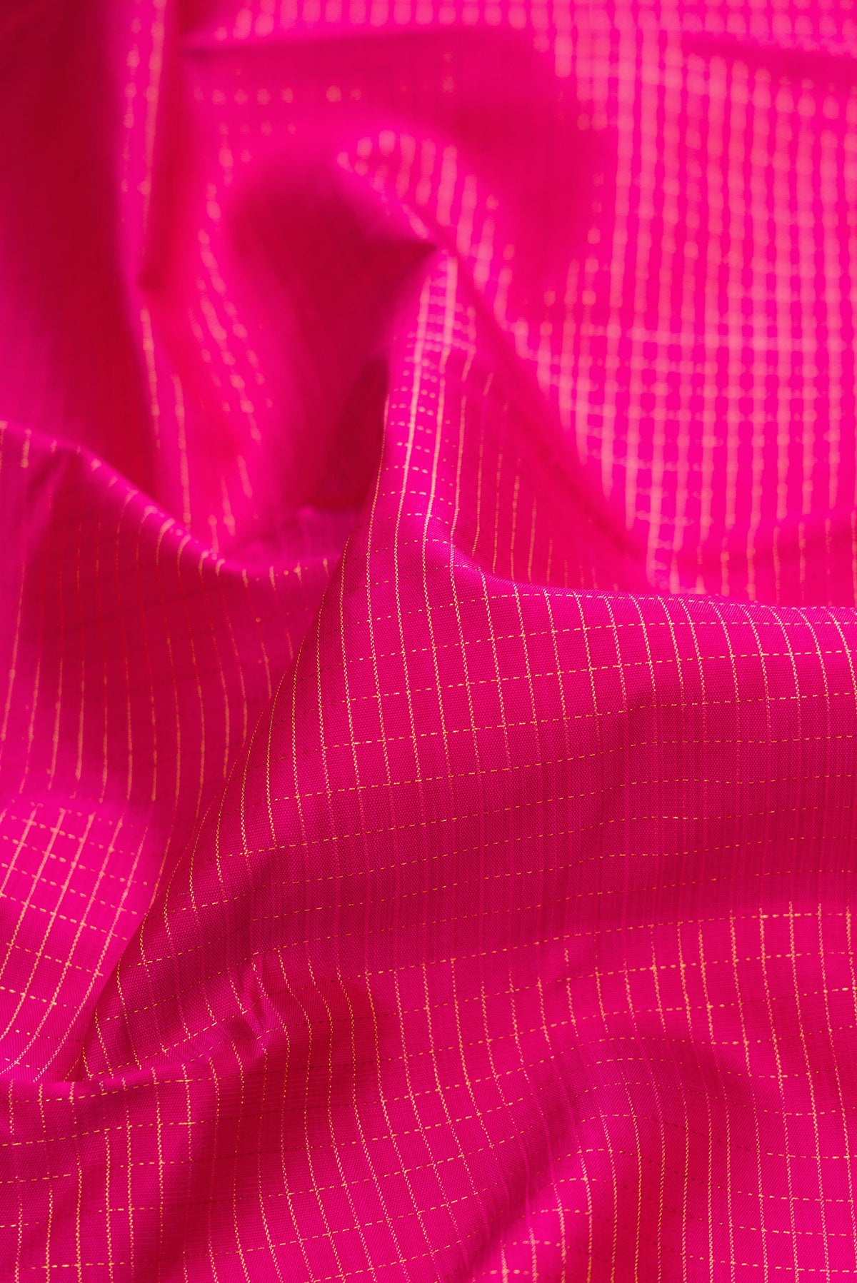 Close up of Pure Silk Rani Pink Kanchipuram Saree with Checked design on the body and Zari Border.  displaying folds