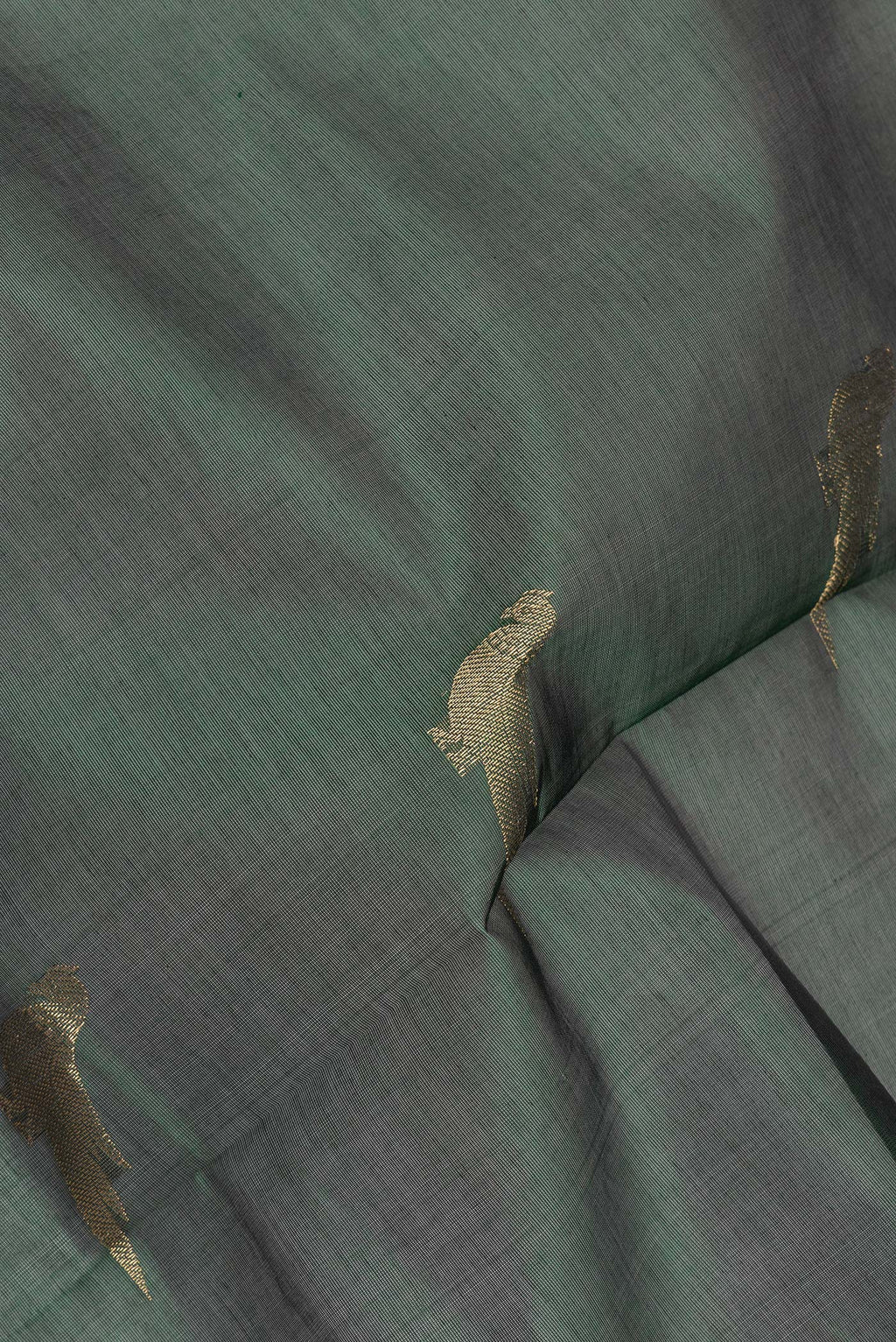 Close up of Bottle Green Silk Cotton Saree with Zari Butta on the body and Zari Border.  displaying folds