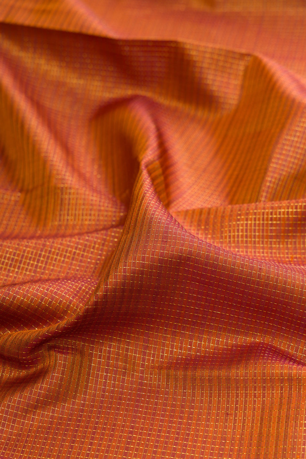 Close up of Rust Kanchipuram Silk Saree with Checked design on the body and Fancy Border.  displaying folds