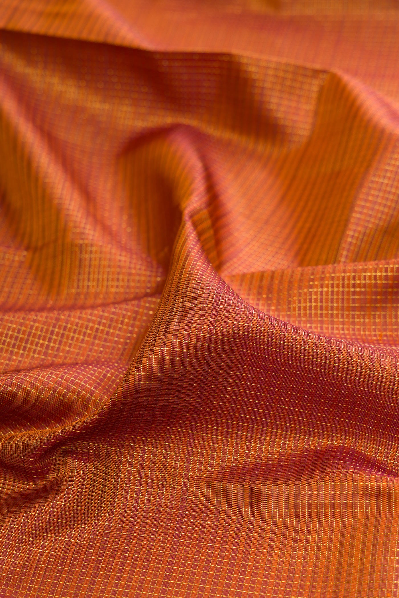 Close up of Rust Kanchipuram Silk Saree with Checked design on the body and Fancy Border.  displaying folds