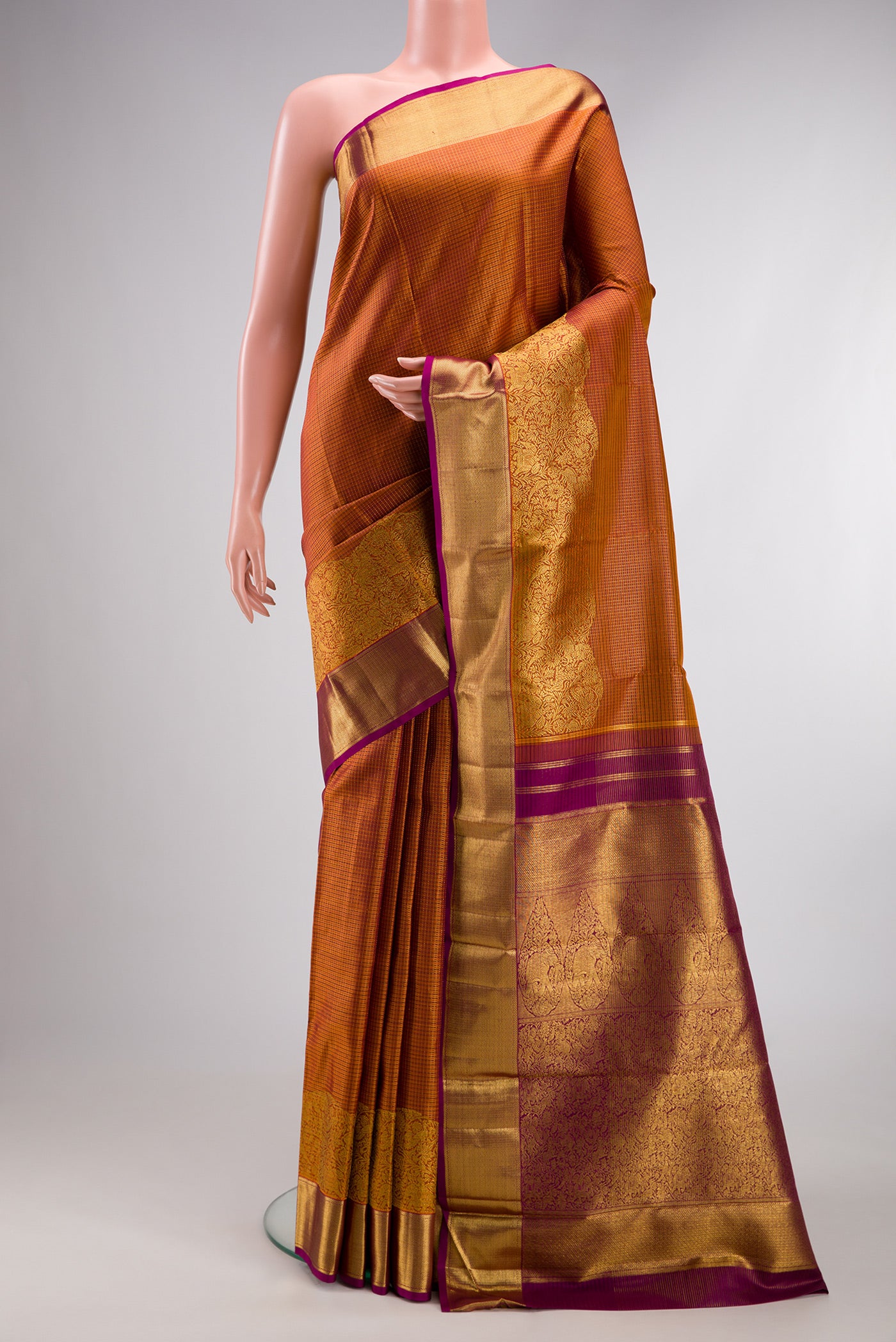 Rust Kanchipuram Silk Saree with Checked design on the body and Fancy Border.  displayed on a mannequin