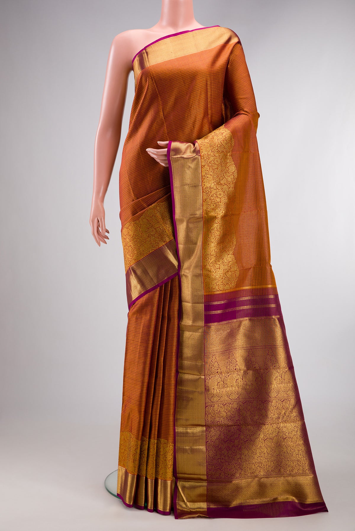 Rust Kanchipuram Silk Saree with Checked design on the body and Fancy Border.  displayed on a mannequin