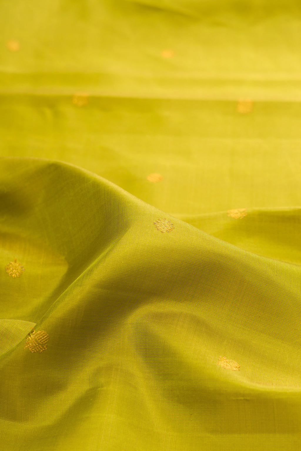 Close up of Green Kanchipuram Silk Saree with Zari Butta on the body and Zari Border.  displaying folds