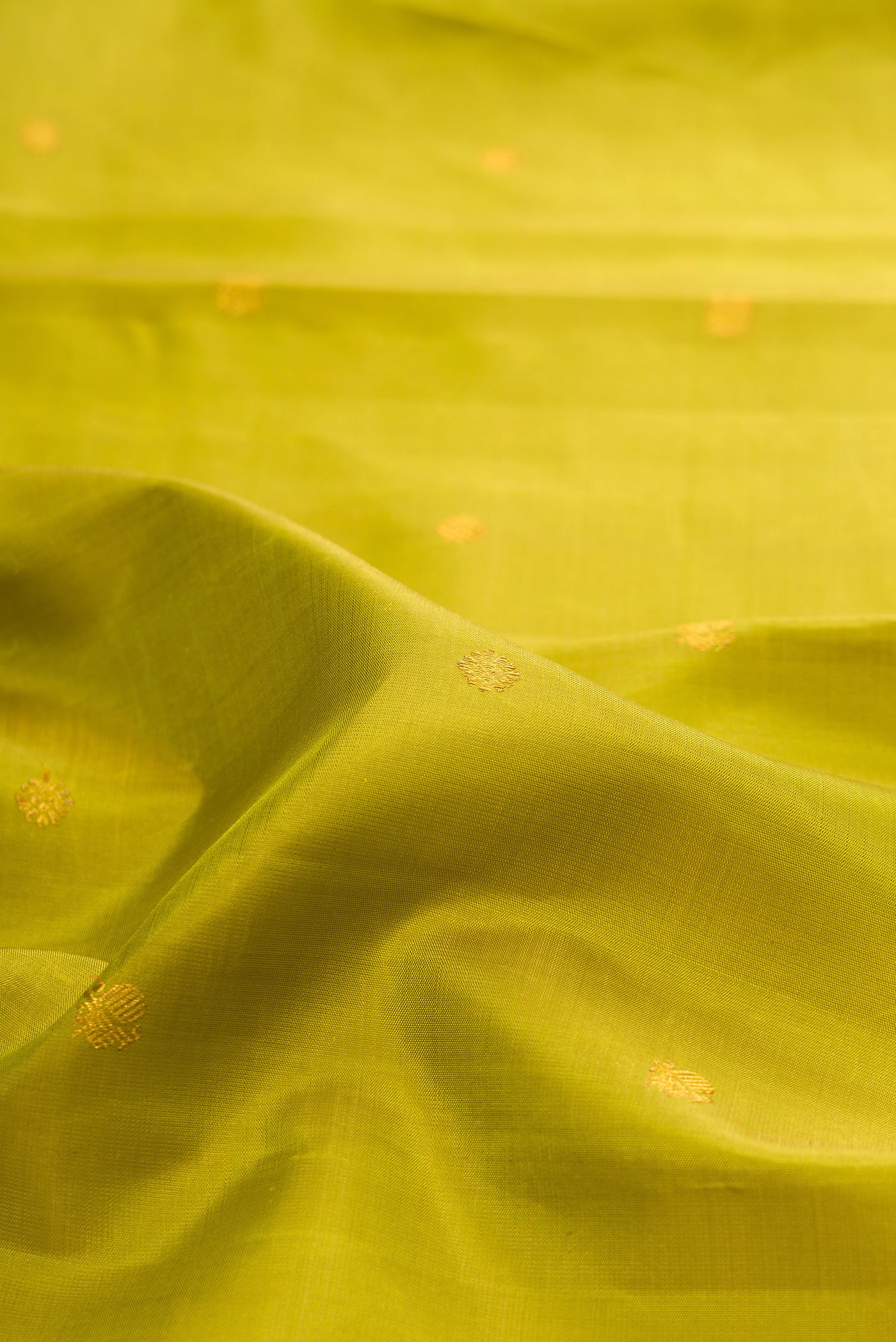 Close up of Green Kanchipuram Silk Saree with Zari Butta on the body and Zari Border.  displaying folds