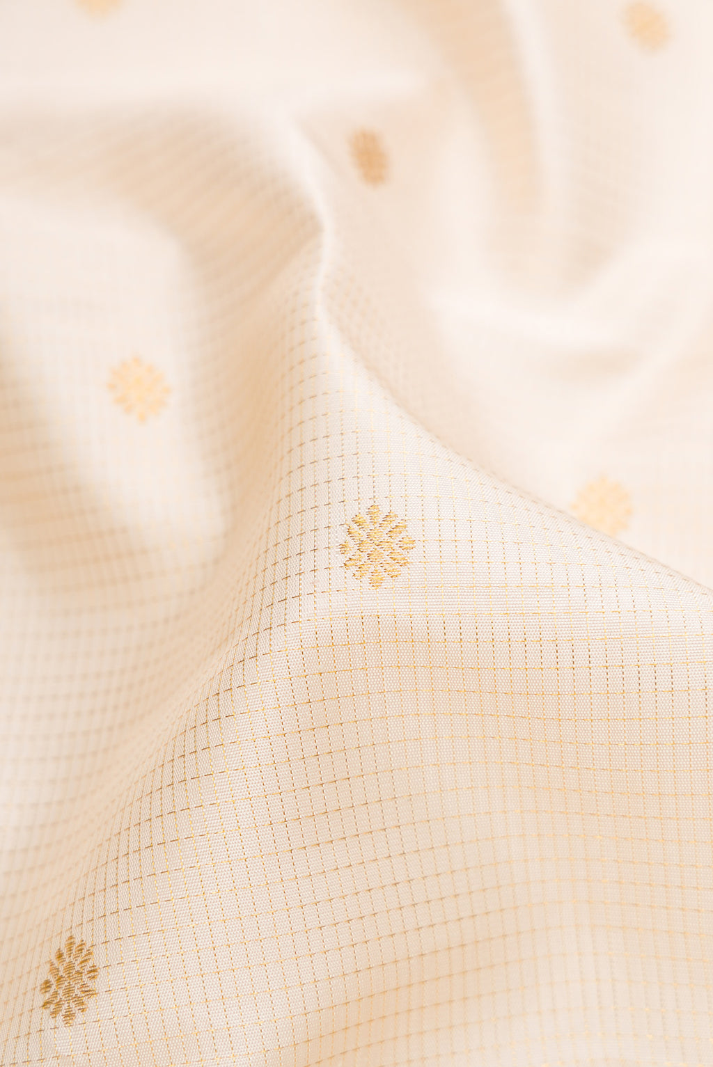 Close up of Cream Kanchipuram Silk Saree with Checked design on the body and Zari Border.  displaying folds