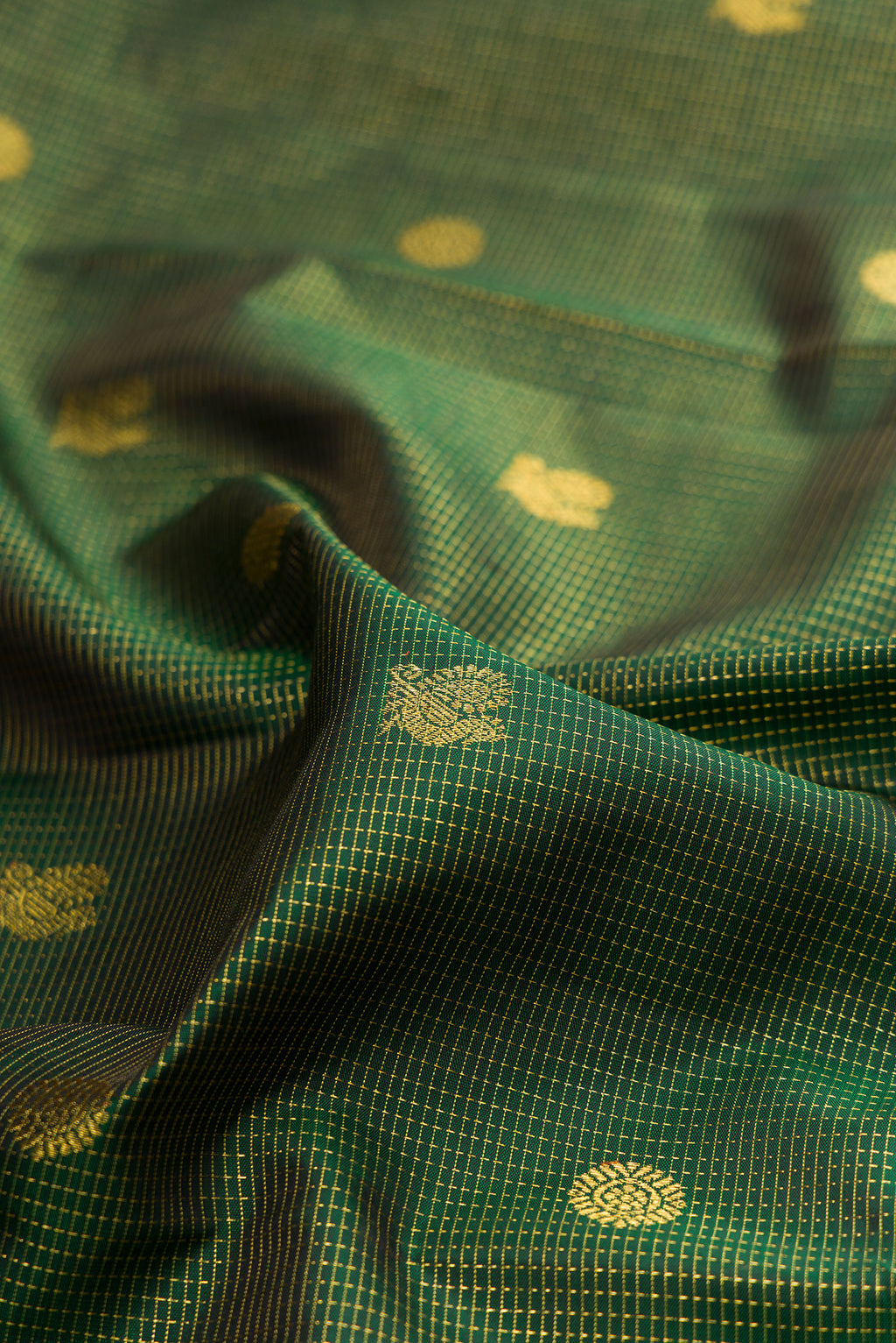 Close up of Bottle Green Kanchipuram Silk Saree with Zari Butta on the body and Zari Border.  displaying folds