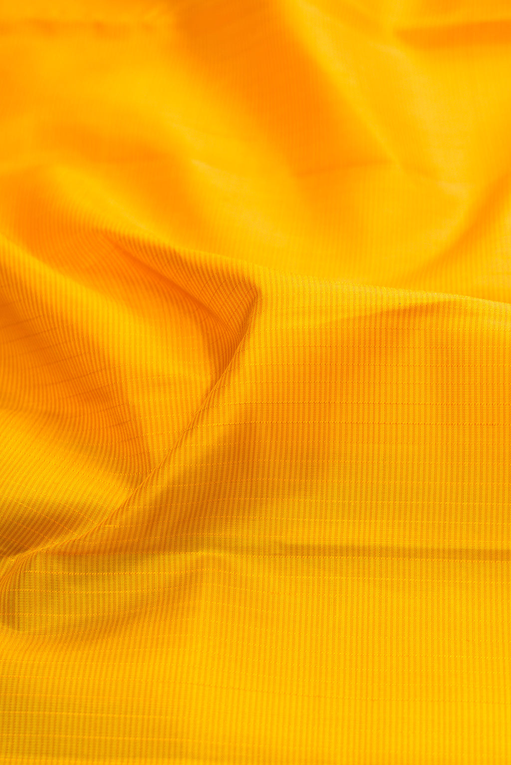 Close up of Yellow Kanjivaram Silk Saree with Stripes on the body and Zari Border.  displaying folds