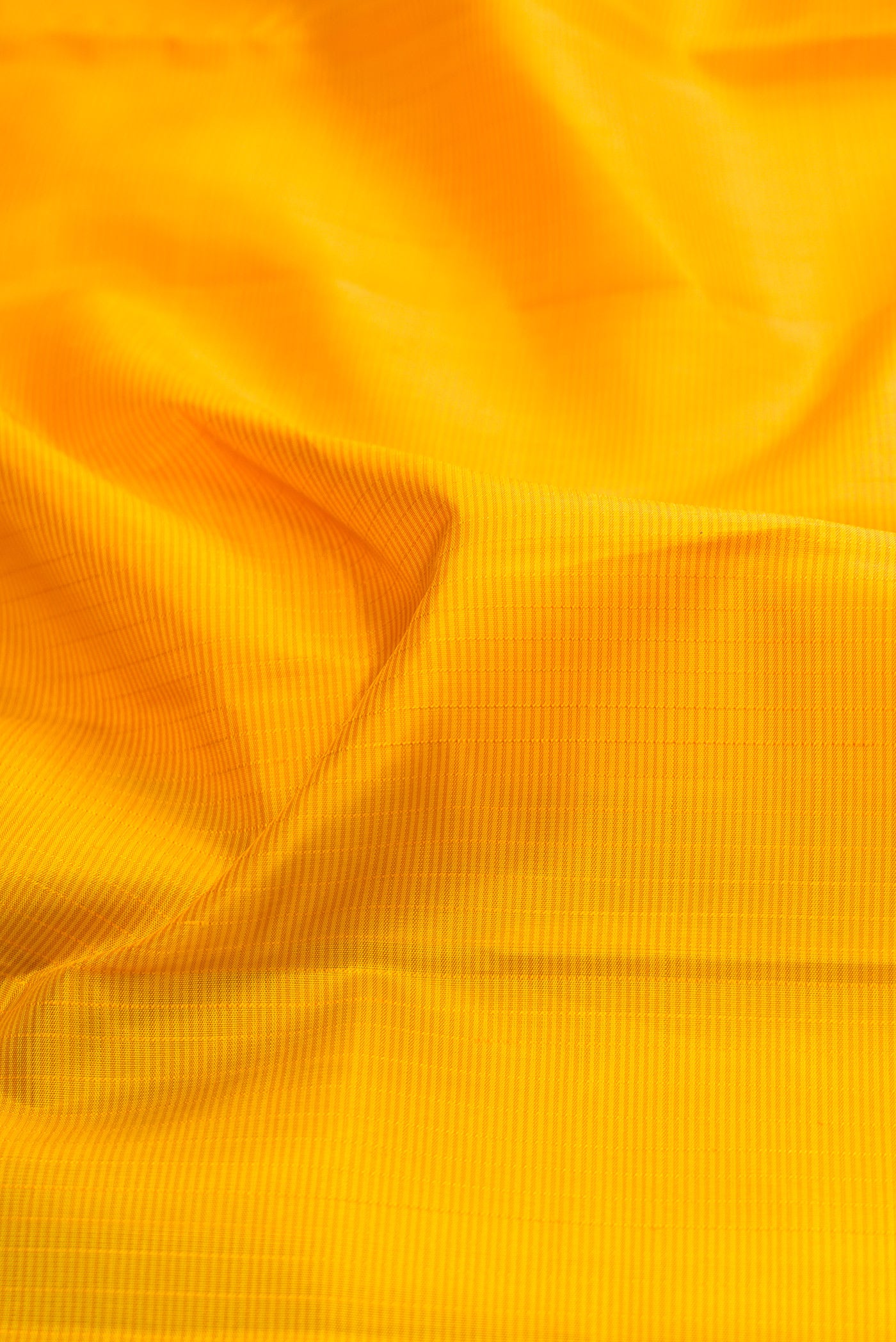 Close up of Yellow Kanjivaram Silk Saree with Stripes on the body and Zari Border.  displaying folds