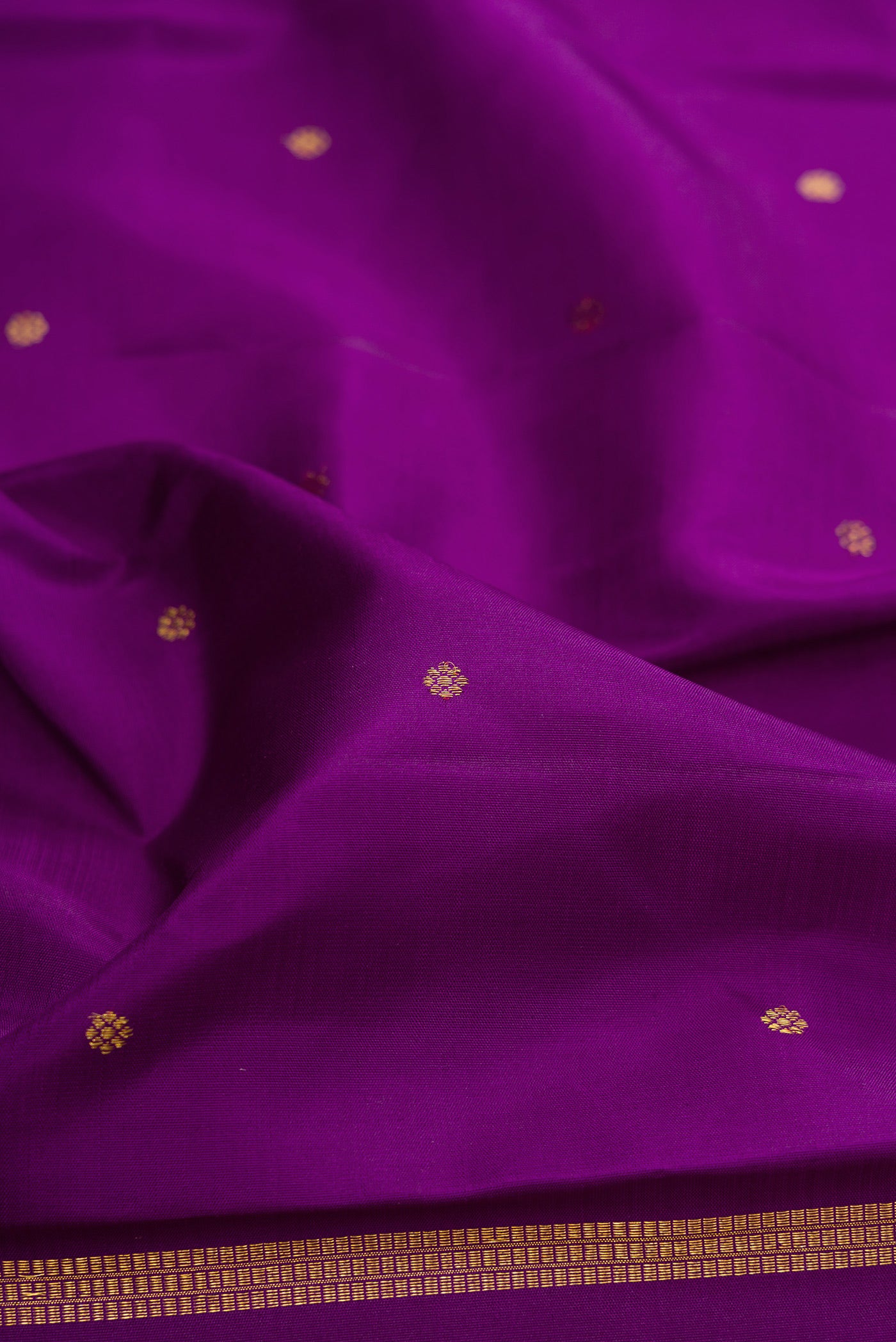 Close up of Purple Kanjivaram Silk Saree with Zari Butta on the body and Fancy Border.  displaying folds