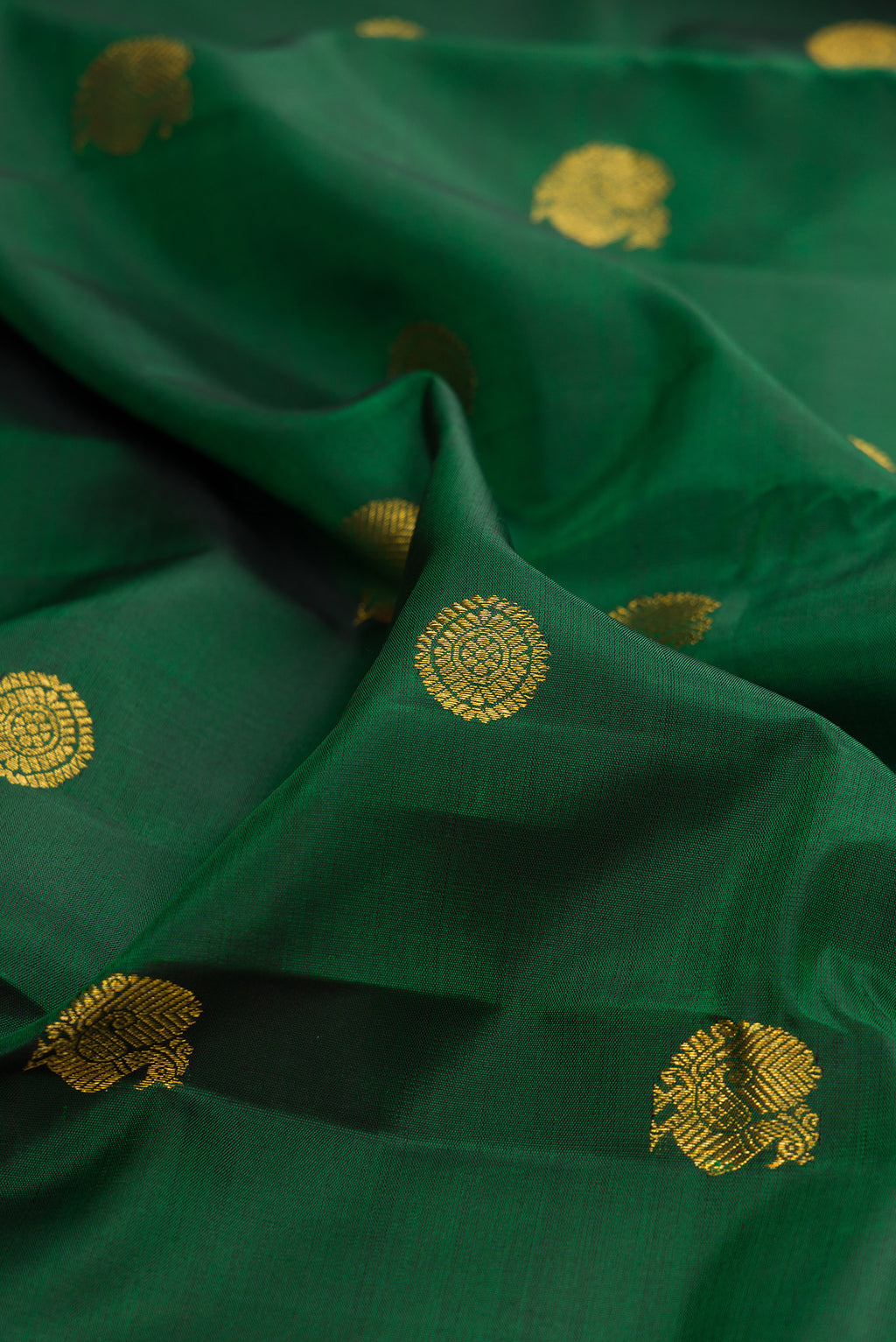 Close up of Bottle Green Kanchipuram Silk Saree with Zari Butta on the body and Zari Border.  displaying folds