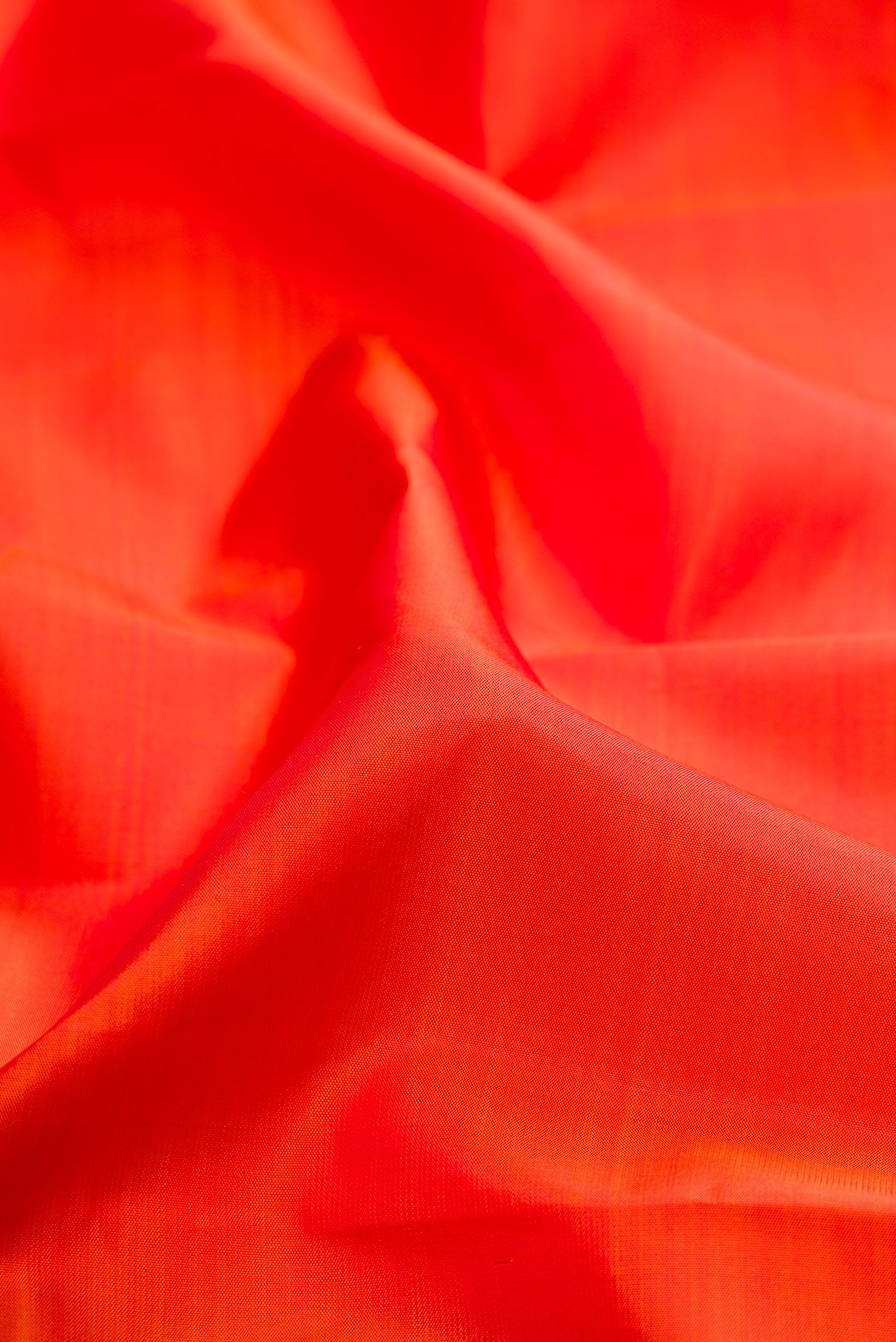 Close up of Orange Kanchipuram Silk Saree with Plain Body and Fancy Border.  displaying folds