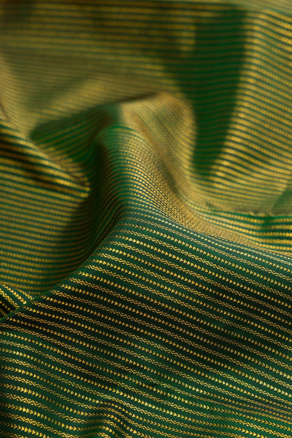 Close up of Pure Silk Bottle Green Kanchipuram Saree with Stripes on the body and Zari Border.  displaying folds